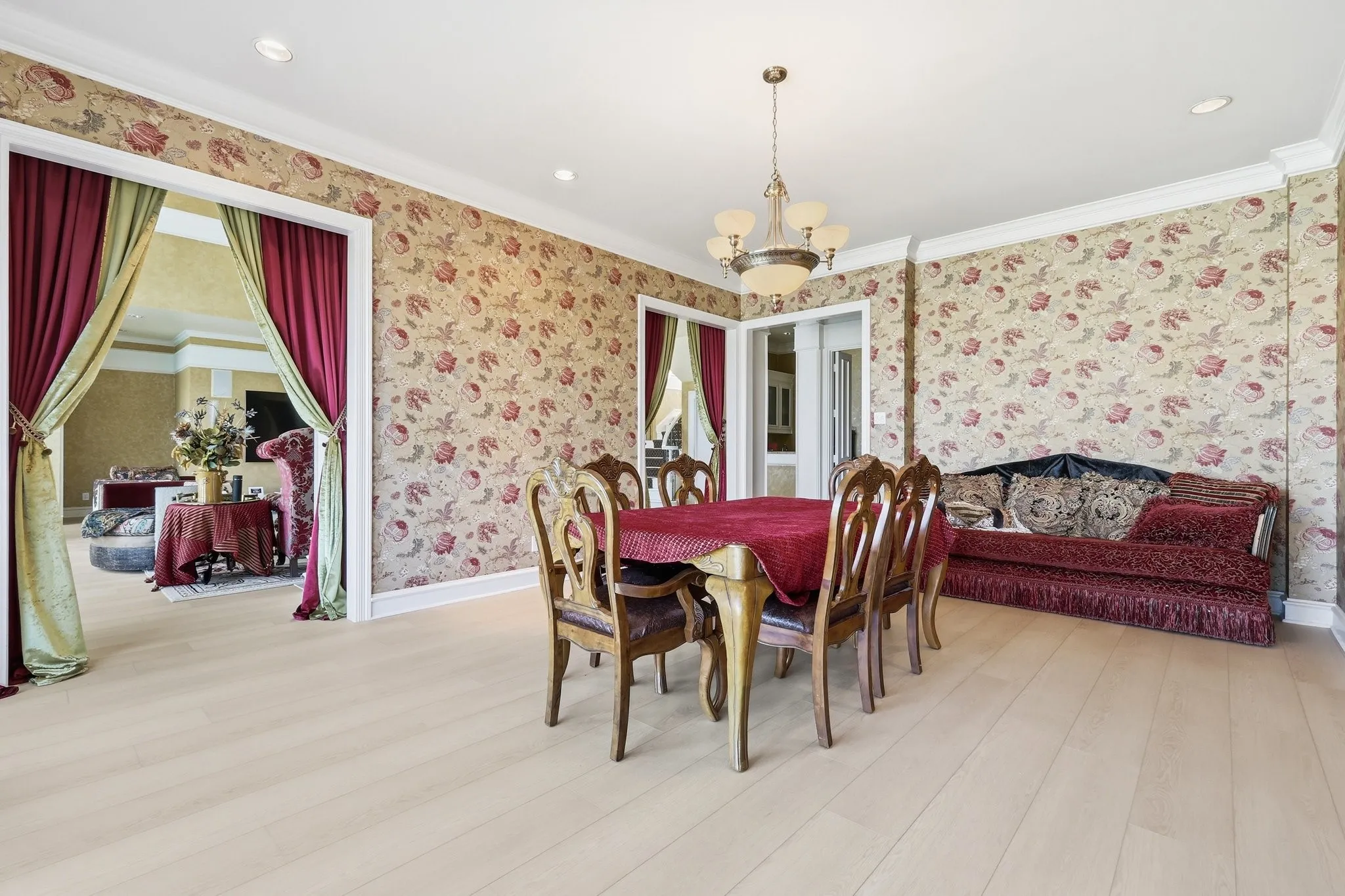 Dining room with hanging lights, light wood-type flooring, ornamental molding, and wallpapered walls
