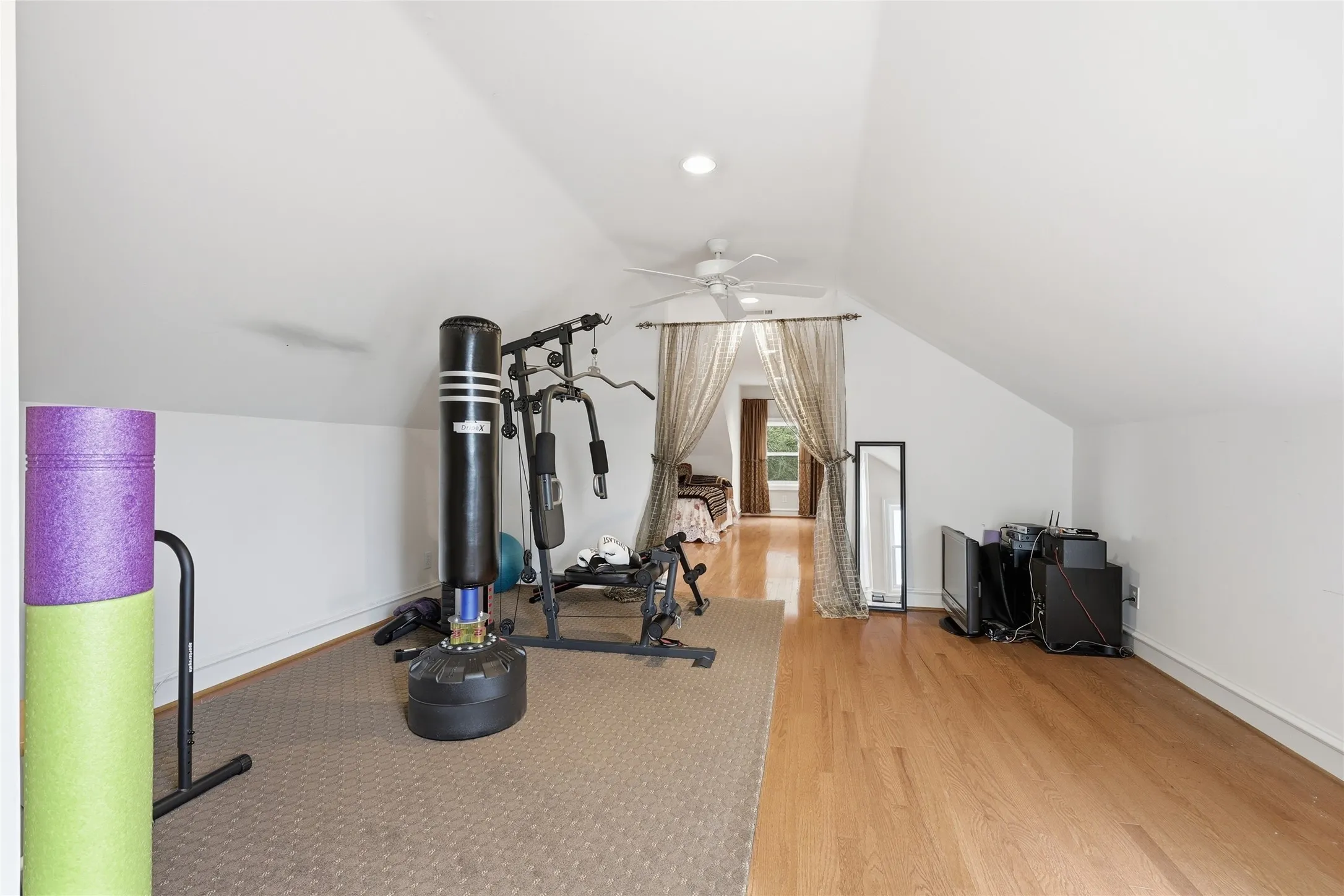 Exercise area with light wood-style flooring and a ceiling fan