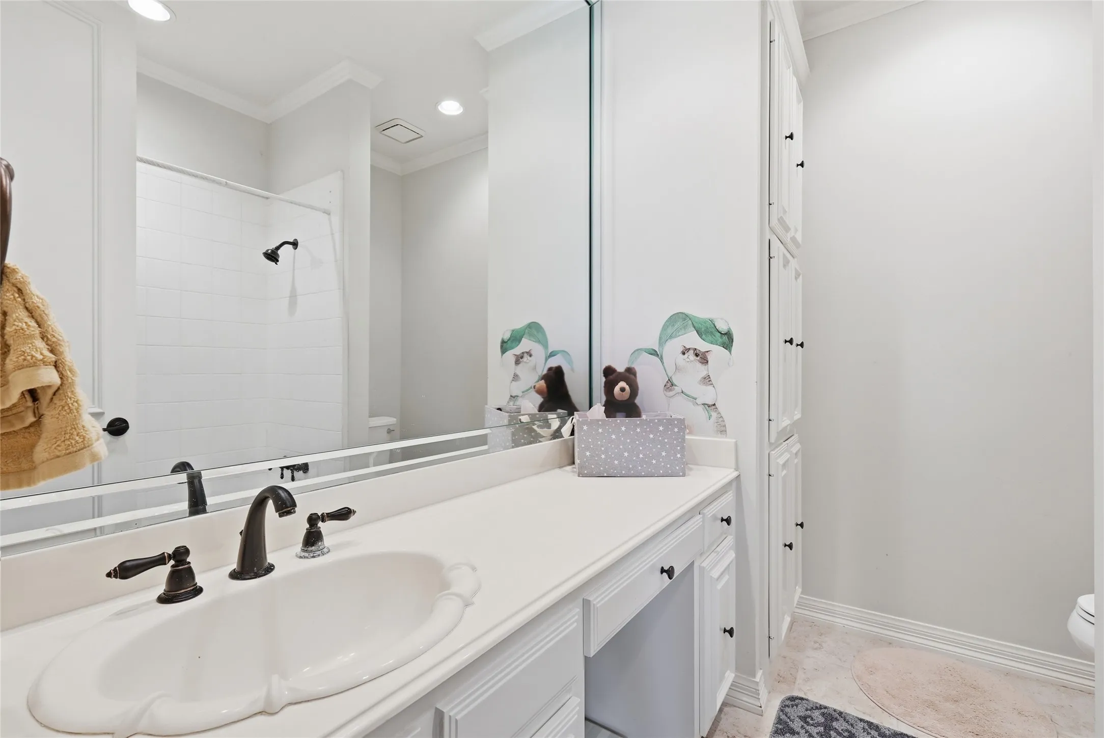 Bathroom featuring vanity, a shower, ornamental molding, and recessed lighting
