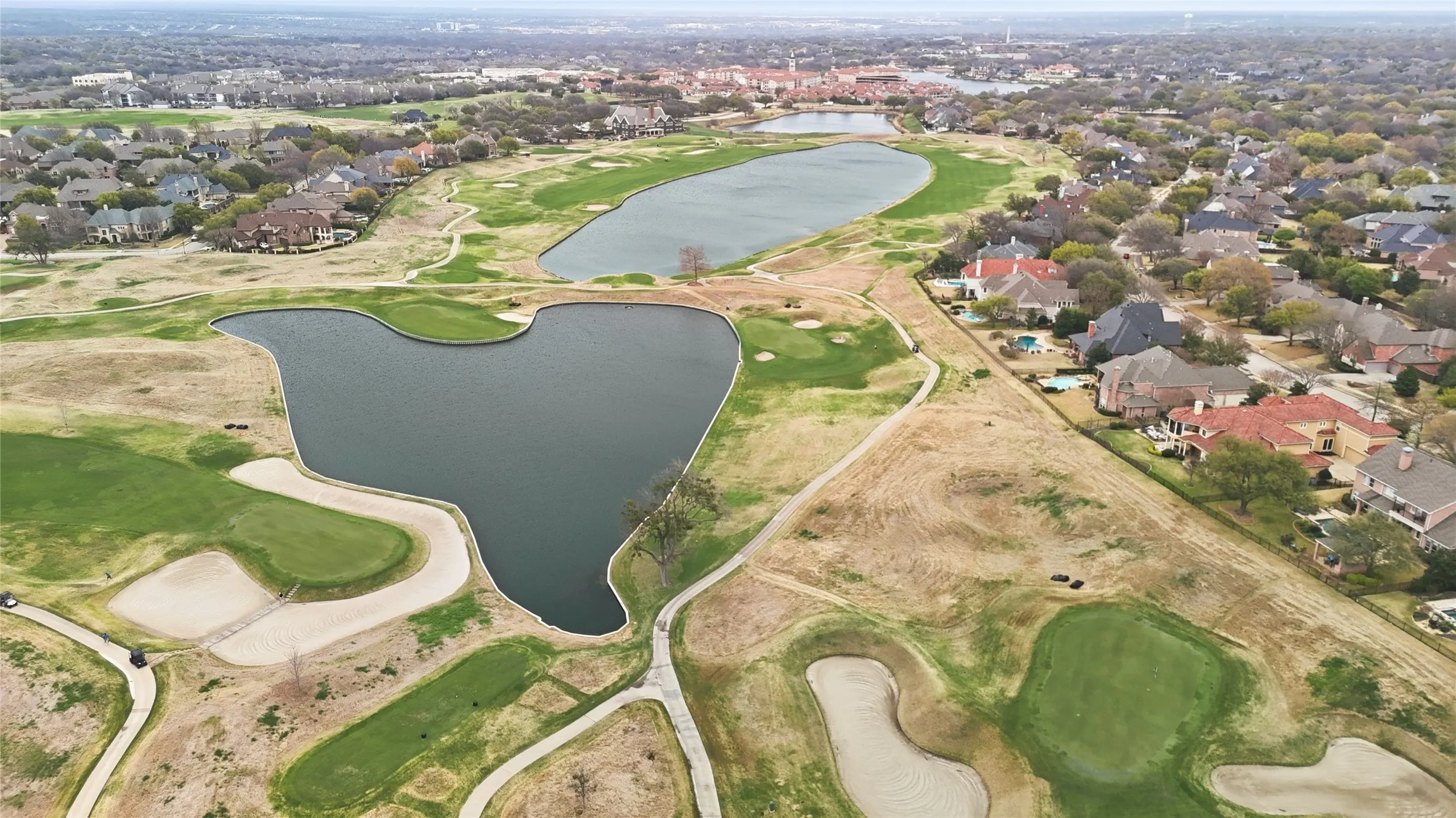 Aerial overview of property's location featuring a local golf course, a nearby body of water, and nearby suburban area
