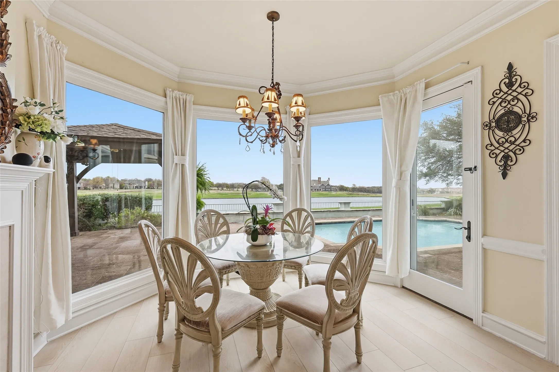 Dining area featuring crown molding, a chandelier, light wood finished floors, plenty of natural light, and a water view