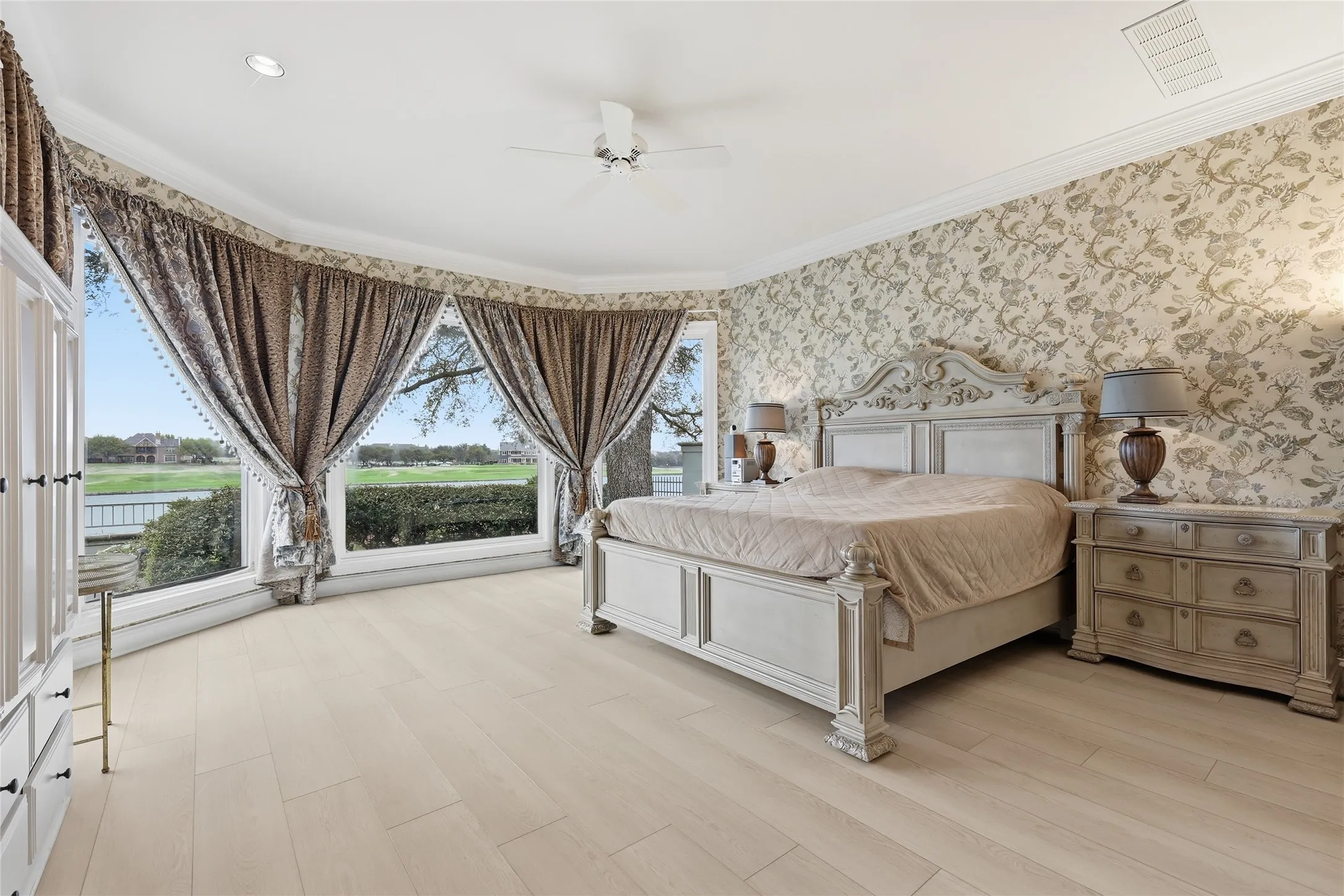 Bedroom with a ceiling fan, ornamental molding, light wood finished floors, and wallpapered walls