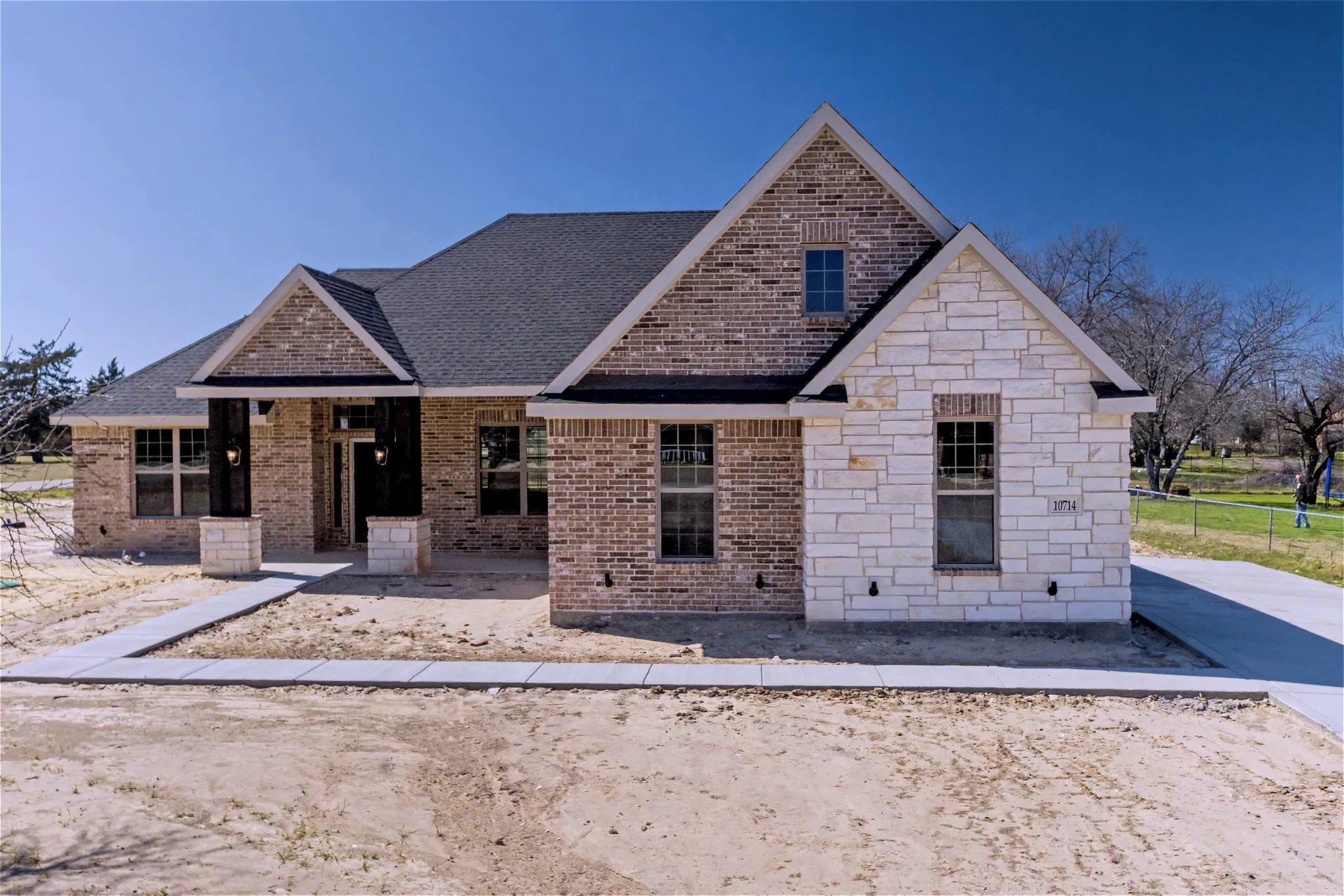 View of front of house with stone siding, brick siding, and a shingled roof
