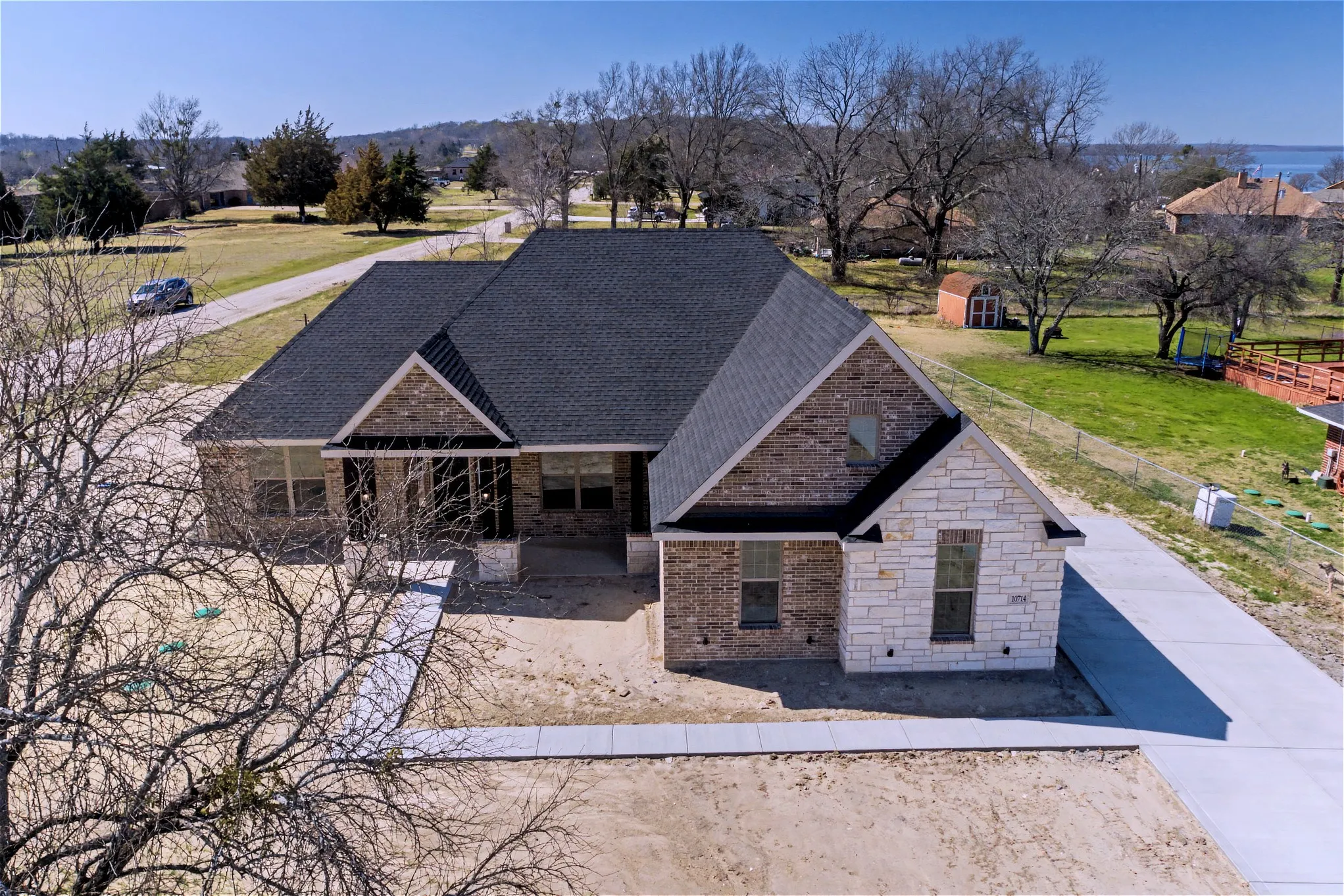 View of front of house with brick siding, roof with shingles, and a front lawn