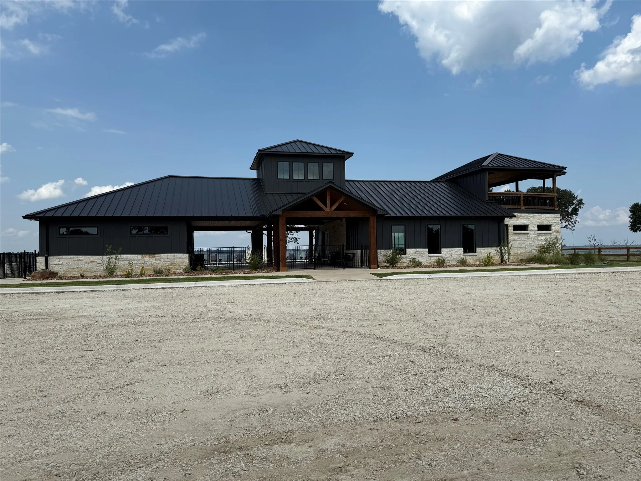 Modern architecture featuring dark vertical siding, light-colored stone veneer, and a dark metal roof