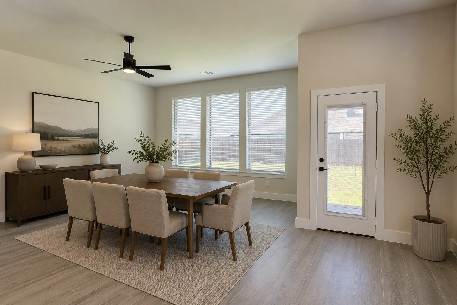 Virtually staged. Spacious dining area featuring wood-finish flooring, a contemporary black ceiling fan, and multiple windows with blinds