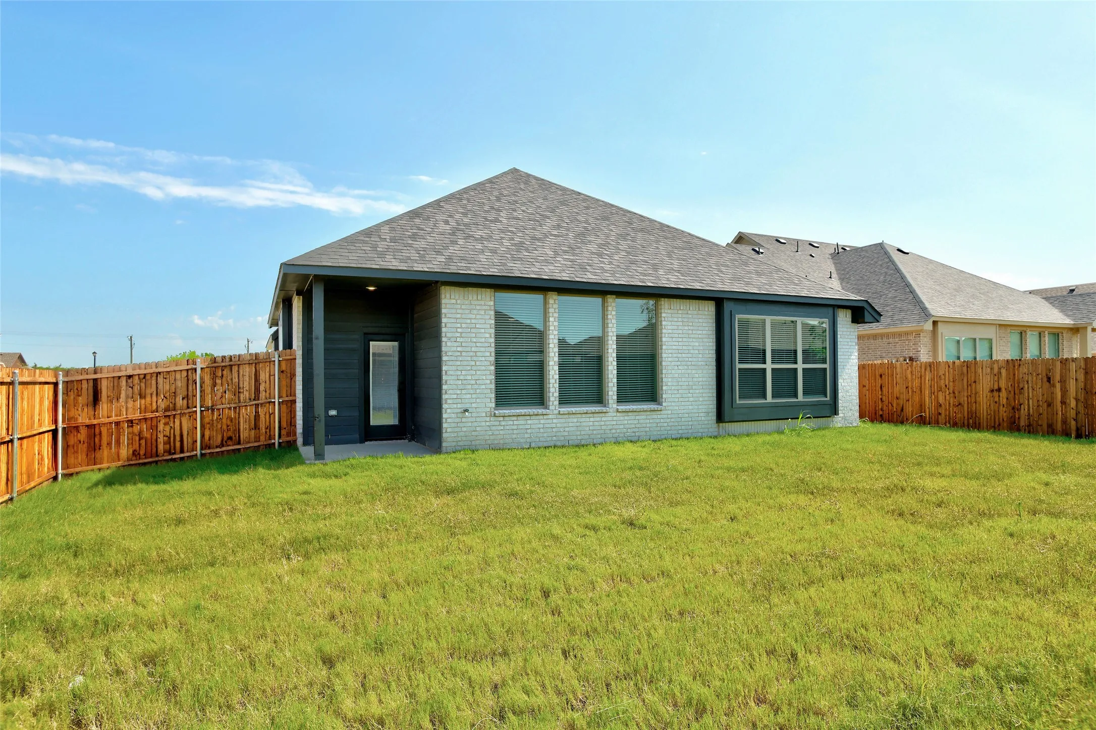 Spacious backyard featuring a privacy fence and a light brick exterior with dark trim