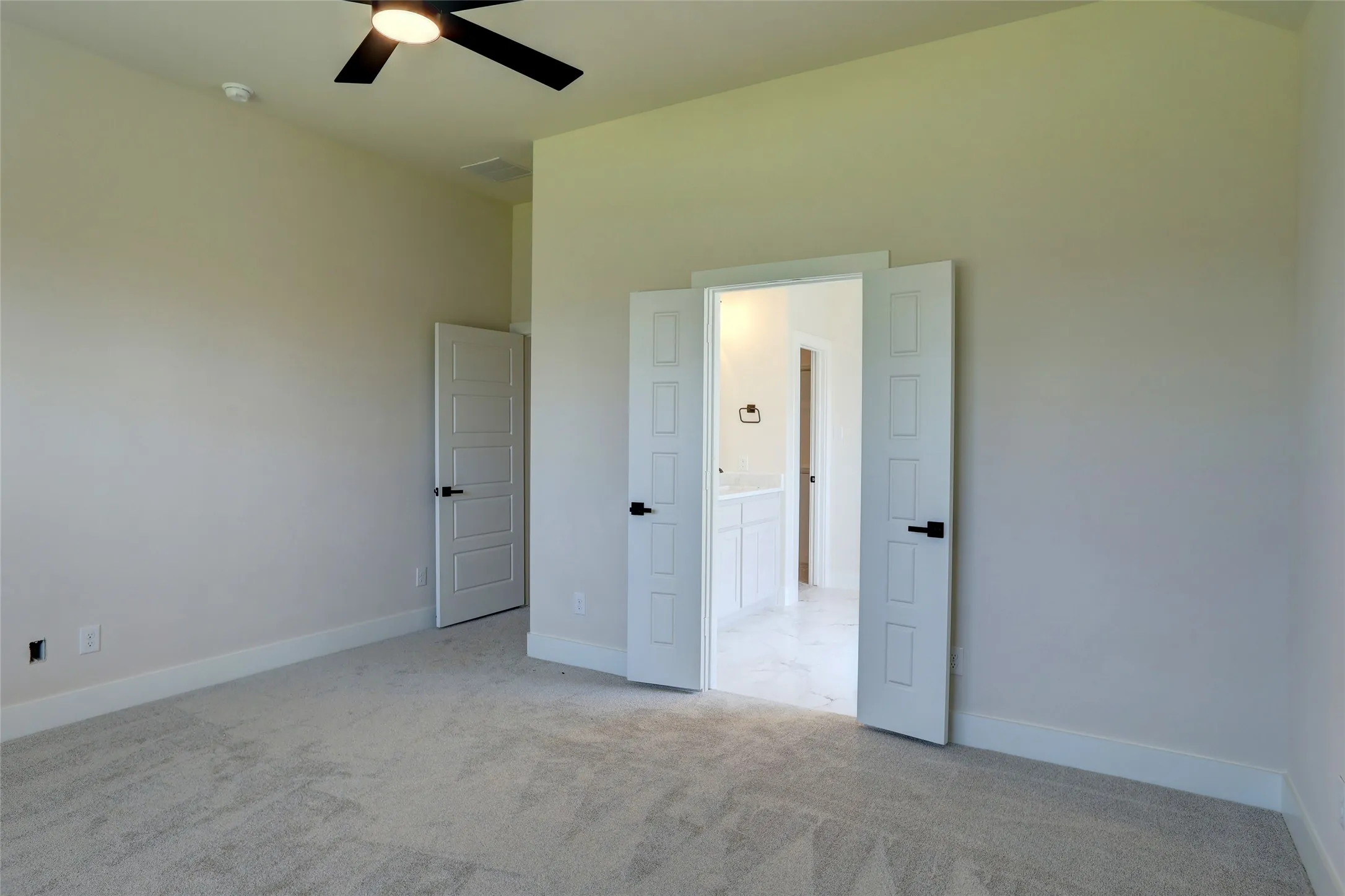 Carpeted interior space featuring light-toned walls and a ceiling fan