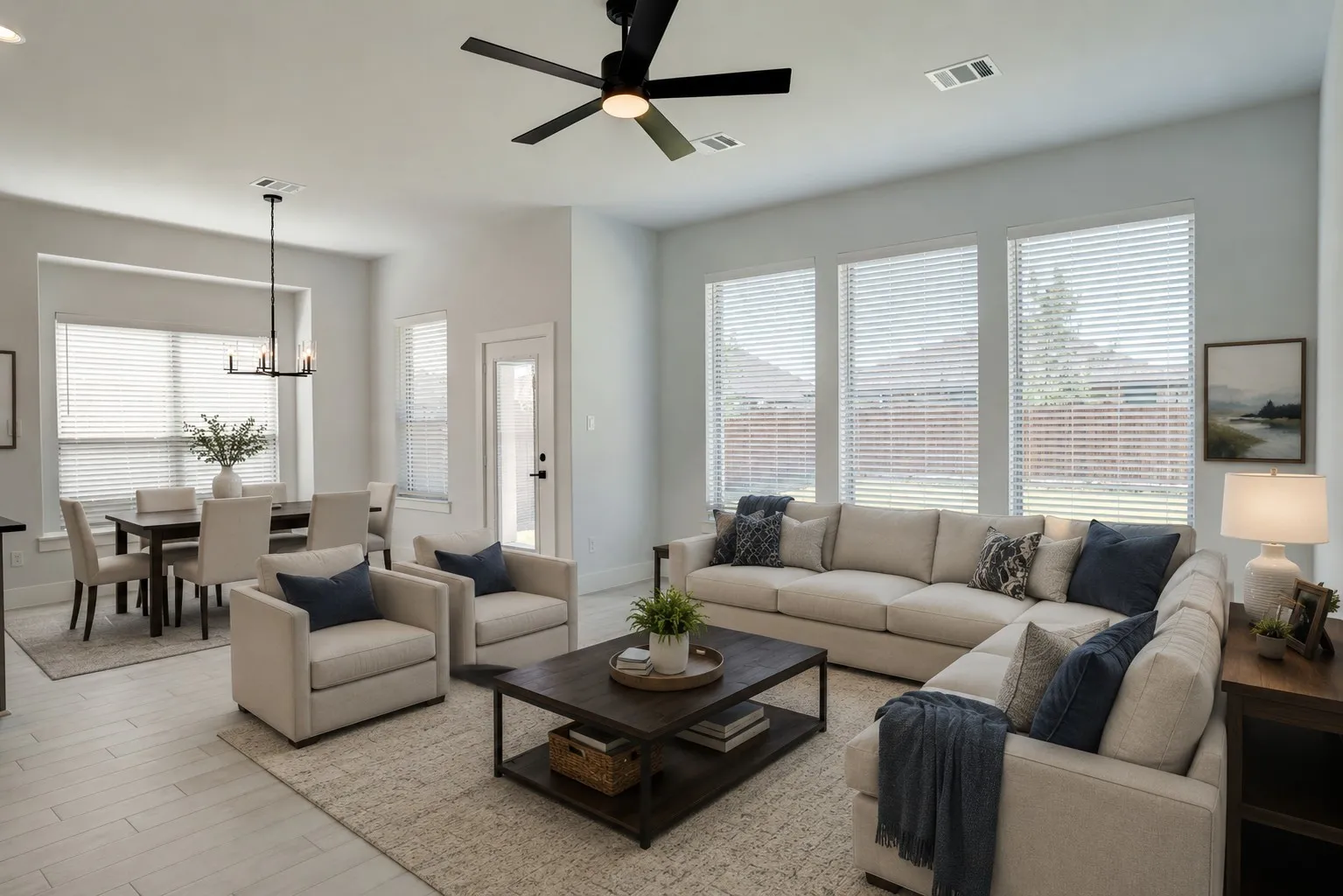 Virtually staged. Open-concept living area with light-toned wood-finish flooring, recessed lighting, a modern ceiling fan, and multiple large windows with blinds