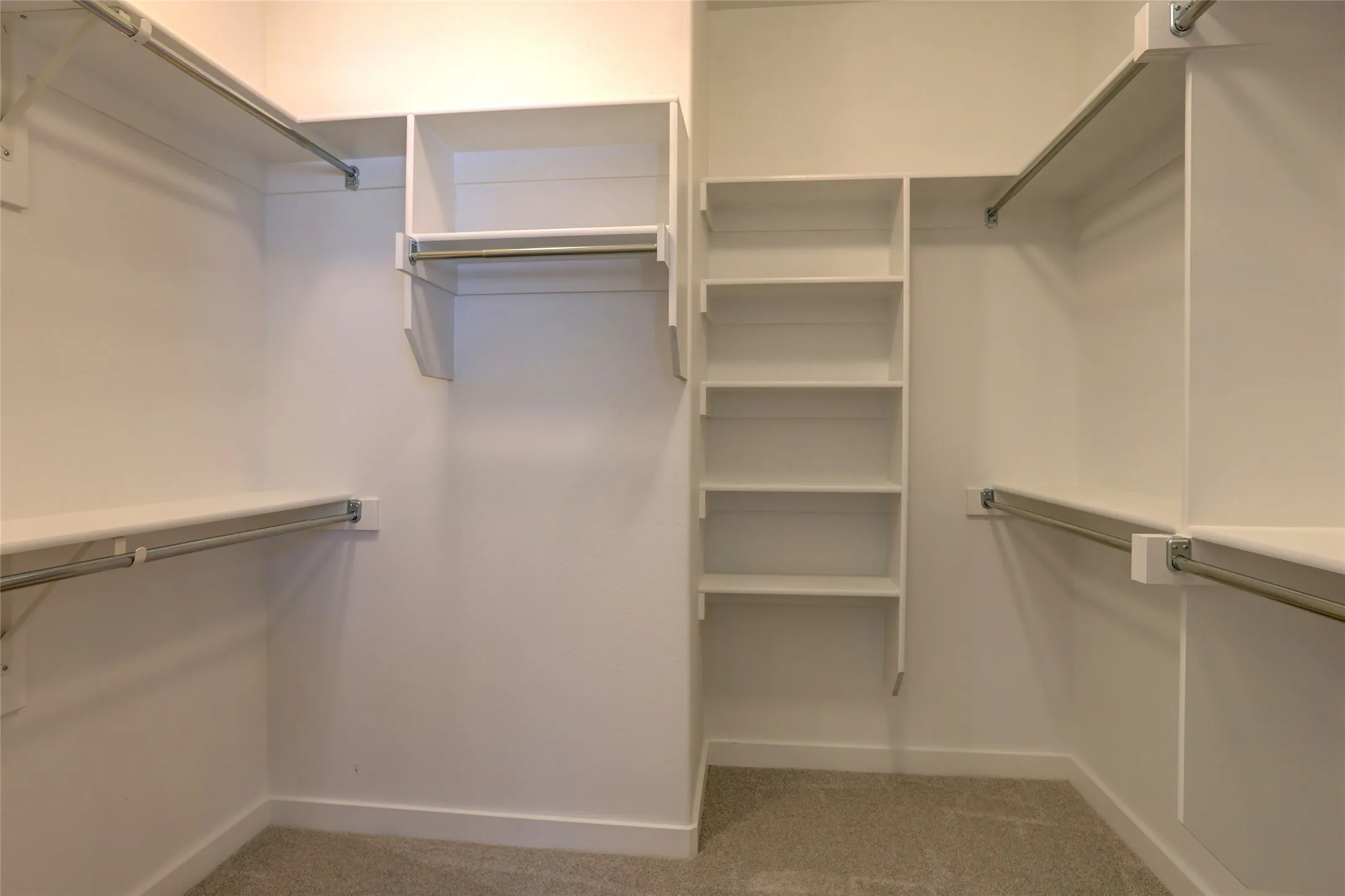Custom closet system featuring multiple hanging rods, integrated shelving units, and plush carpet flooring