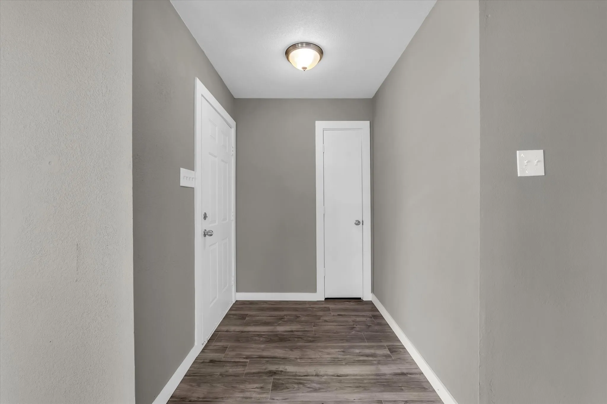 Hall featuring dark wood-type flooring and baseboards