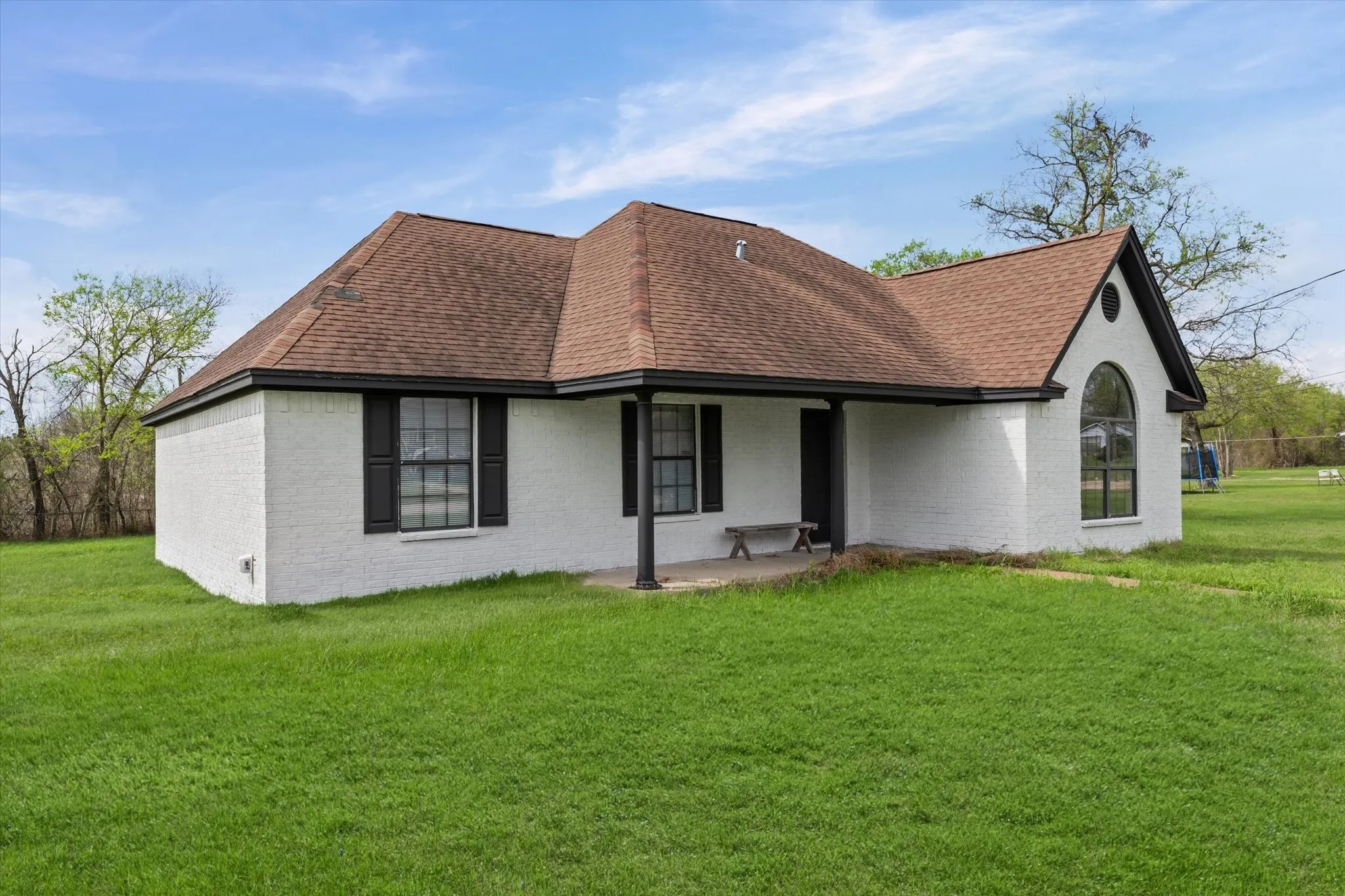 Front of property with a shingled roof, a yard and brick siding