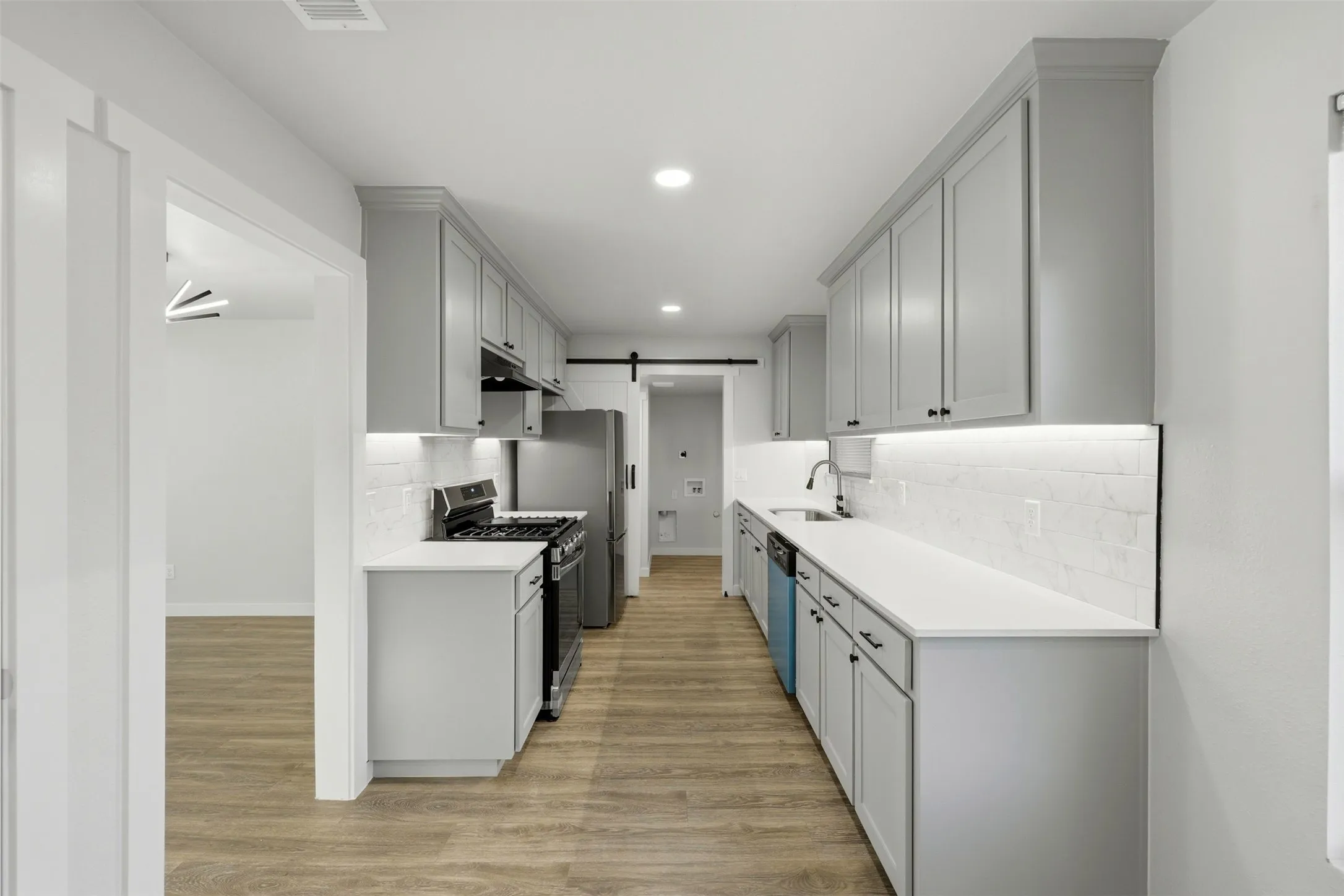 Kitchen with sliding barn door to full size utility room.