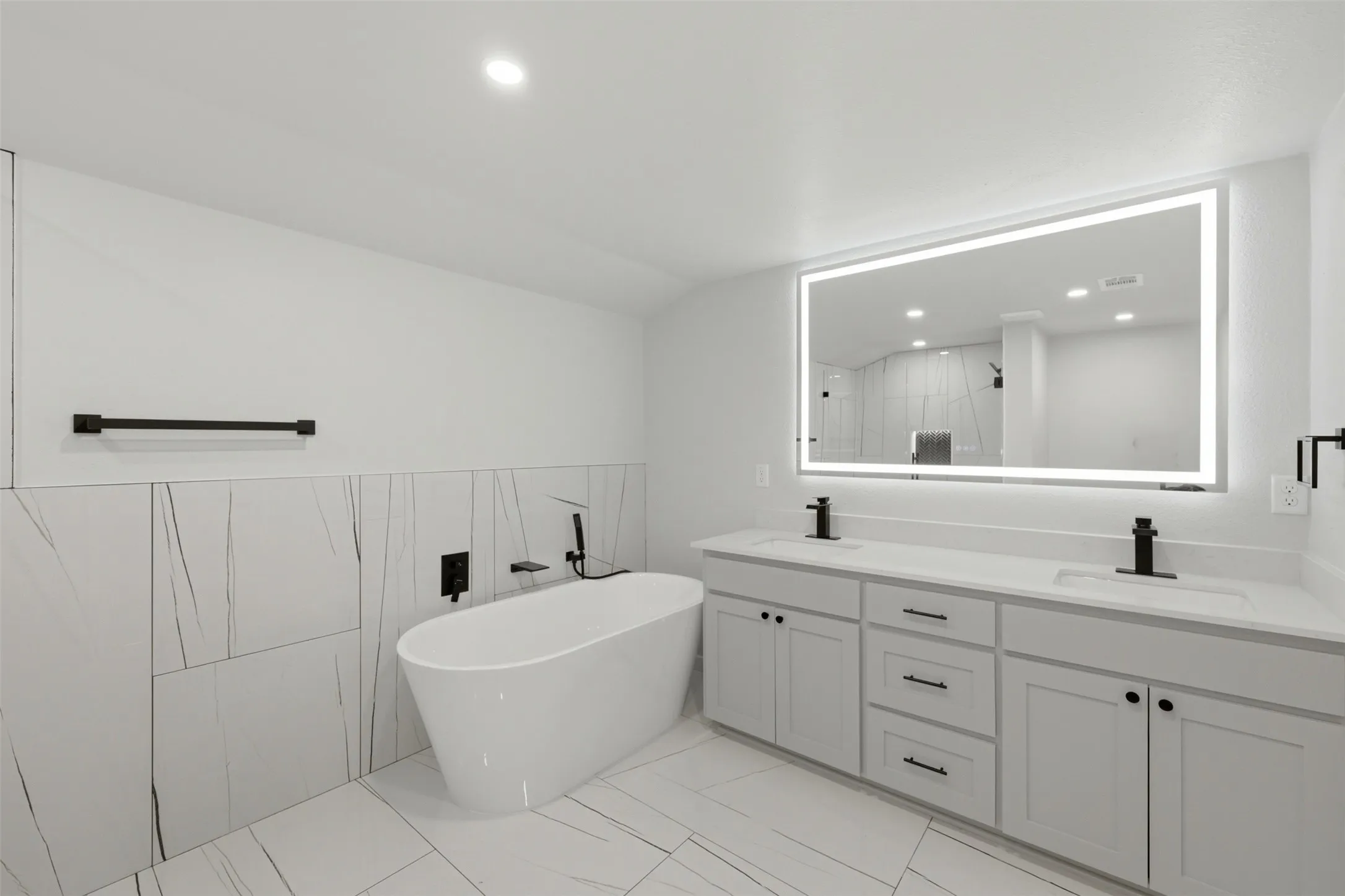 Gorgeous fully remodeled primary bath with led mirror, double vanities, free standing tub, and large beautifully tiled walk-in-shower.