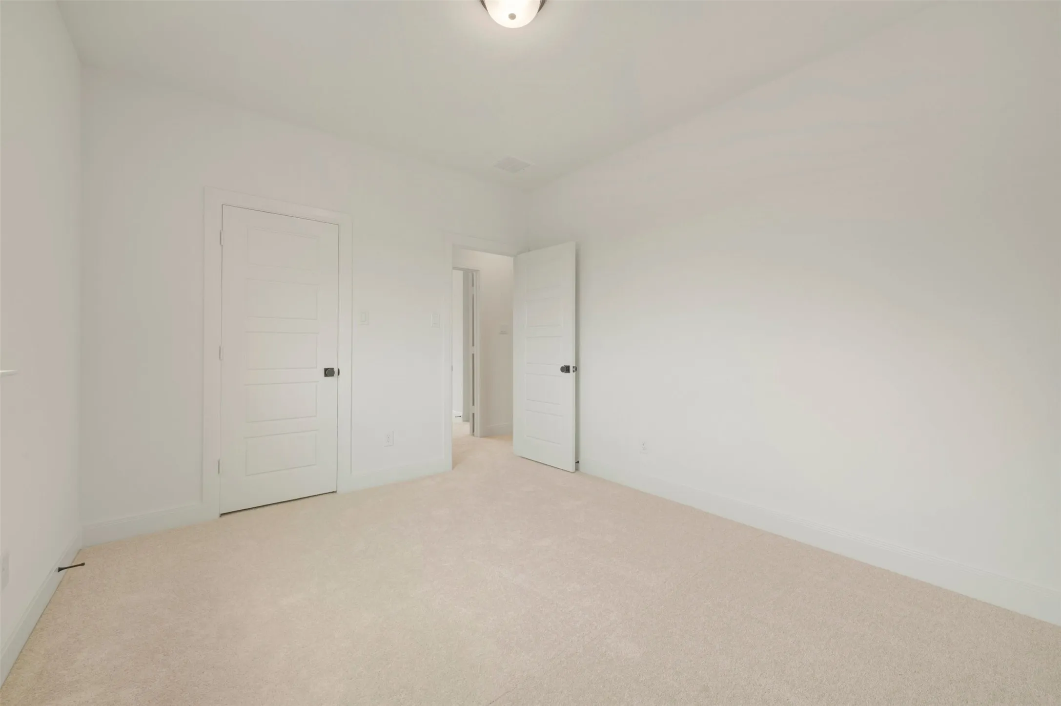 Neutral interior room featuring light-toned carpeting and white walls