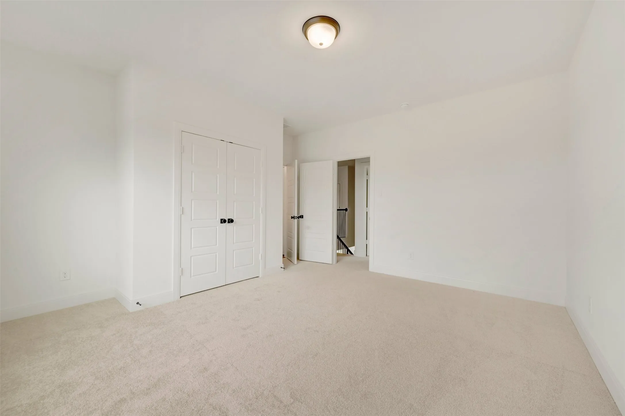 Neutral tone carpeting, white walls, and a semi-flush ceiling light fixture