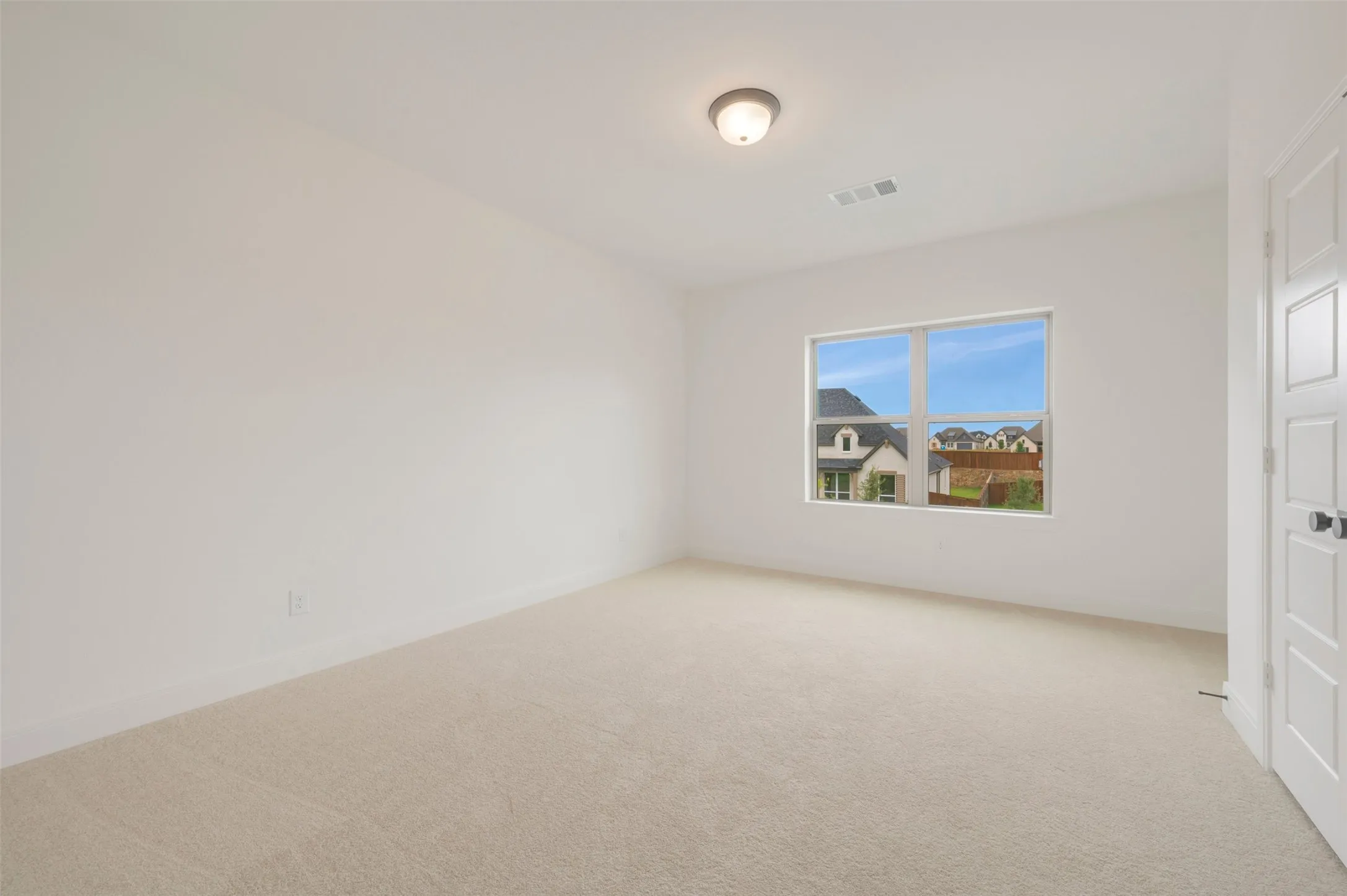Carpeted room with a single window, white walls, and a flush-mount ceiling light