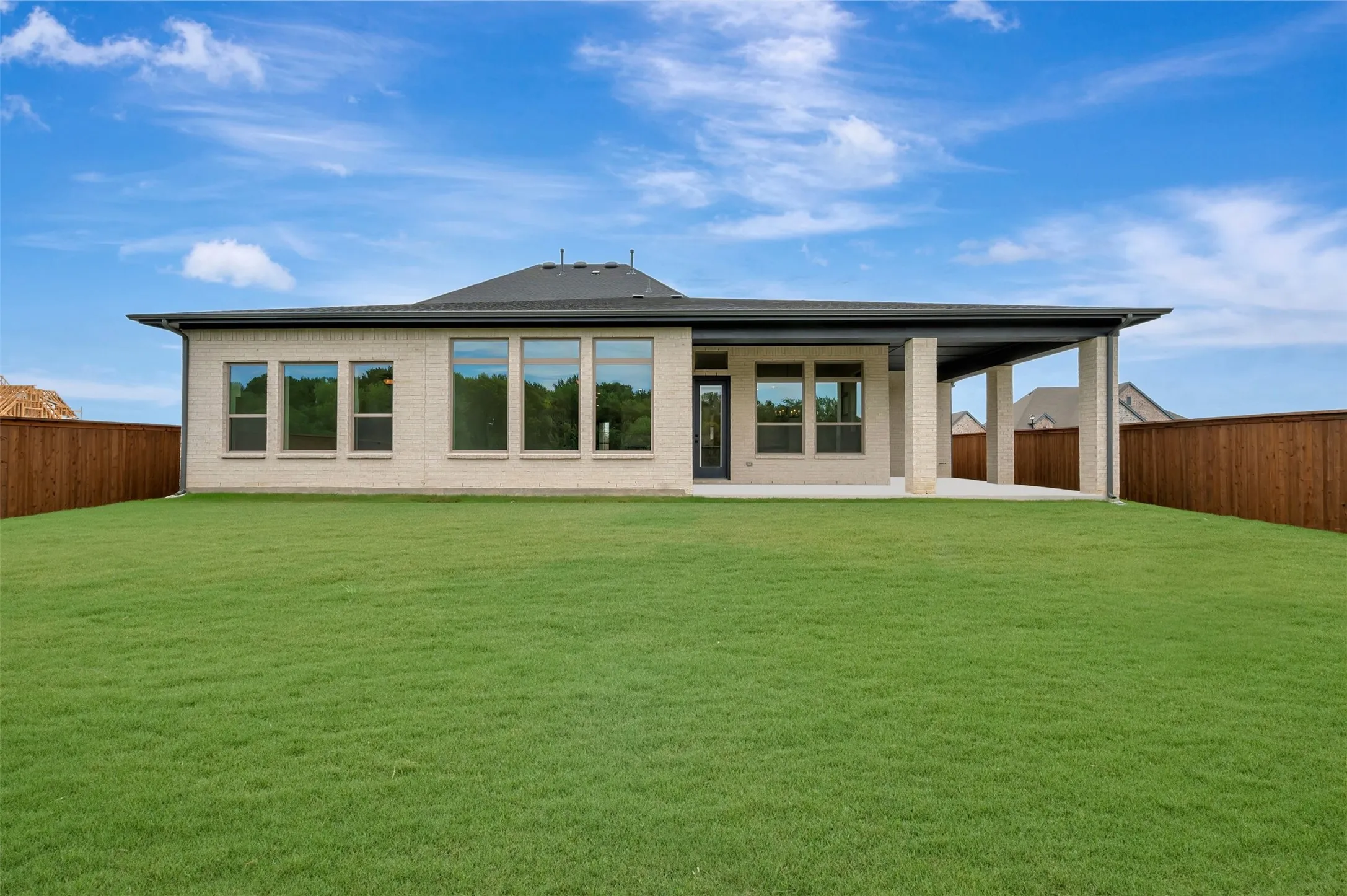 Expansive green lawn with a newly constructed brick exterior