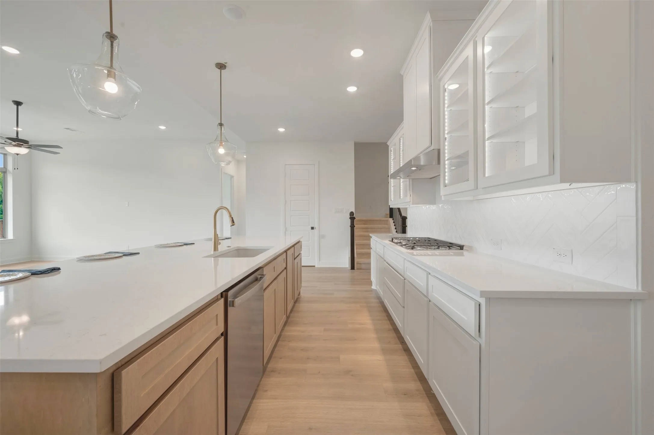 Open-concept kitchen featuring an expansive island with an undermount sink, brass faucet, and integrated dishwasher