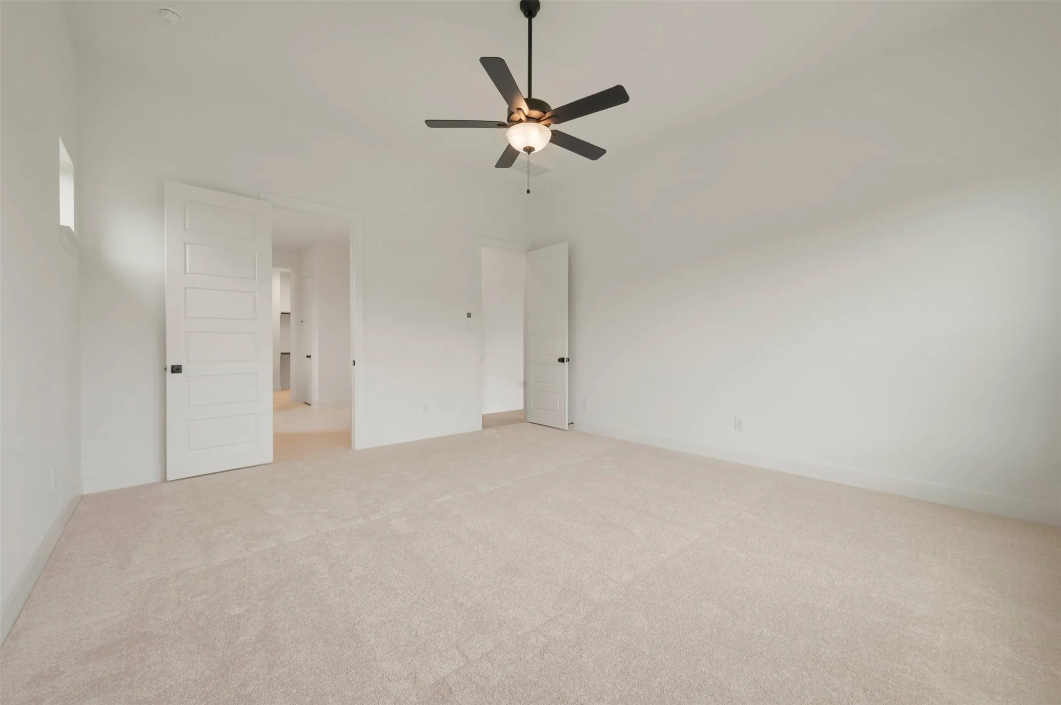 Spacious room featuring neutral carpeting, a ceiling fan with integrated lighting, and crisp white walls