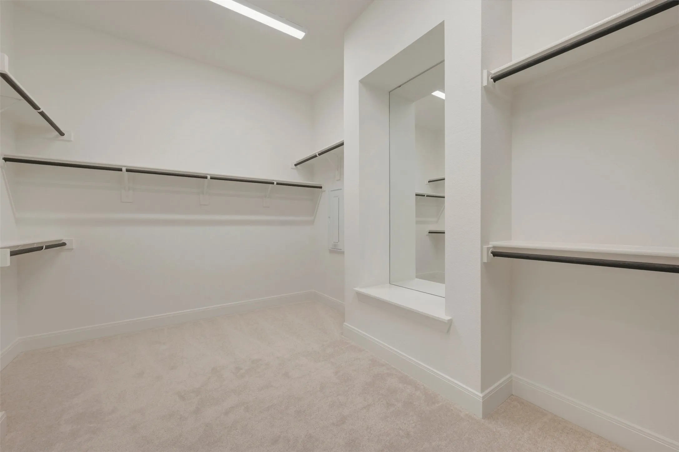 Spacious walk-in closet featuring light beige carpeting, extensive shelving, integrated clothing rods, a full-length mirror, and recessed lighting