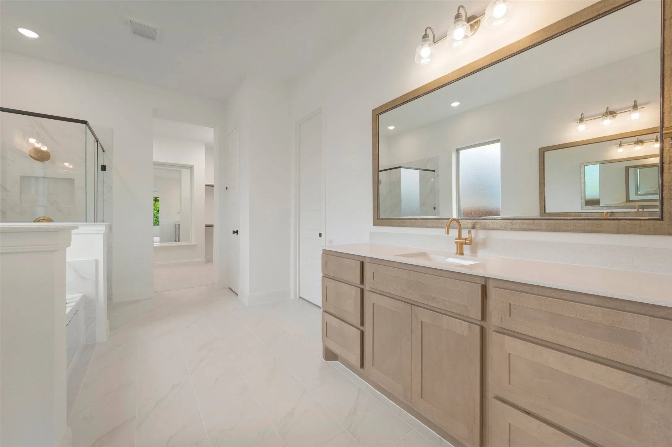 Spacious bathroom featuring a long wood-finish vanity with a light-toned countertop and single basin
