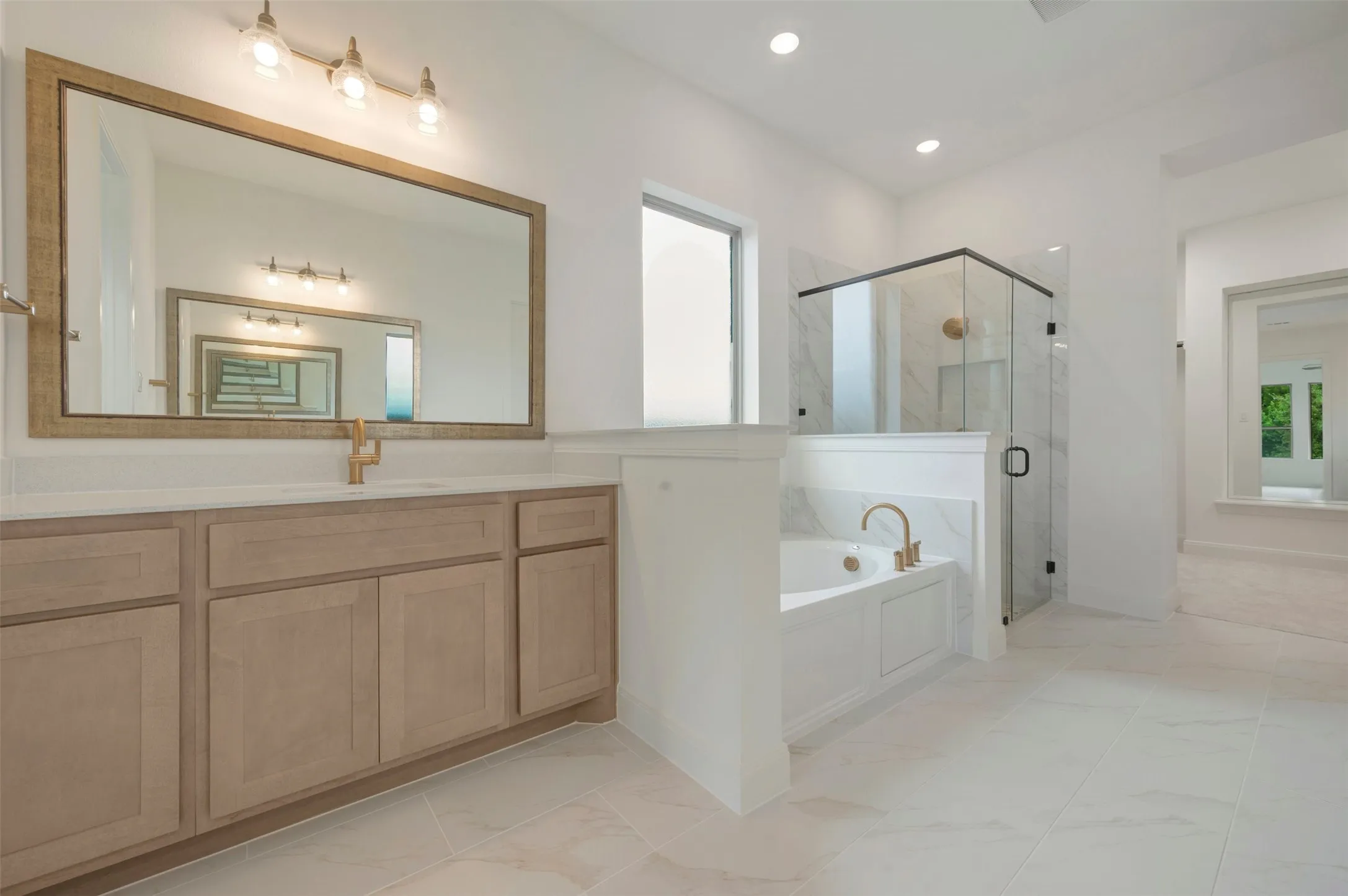 Modern bathroom featuring a wood-finish vanity with a large framed mirror and three-light fixture