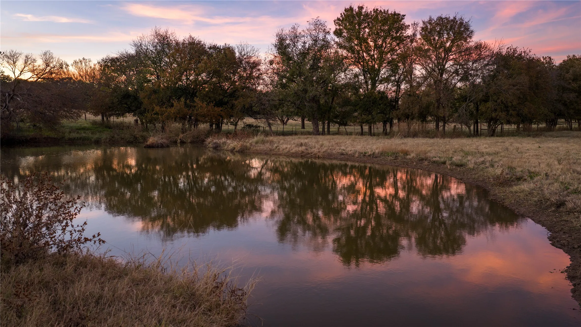 Pond reflecting colorful sunset sky.