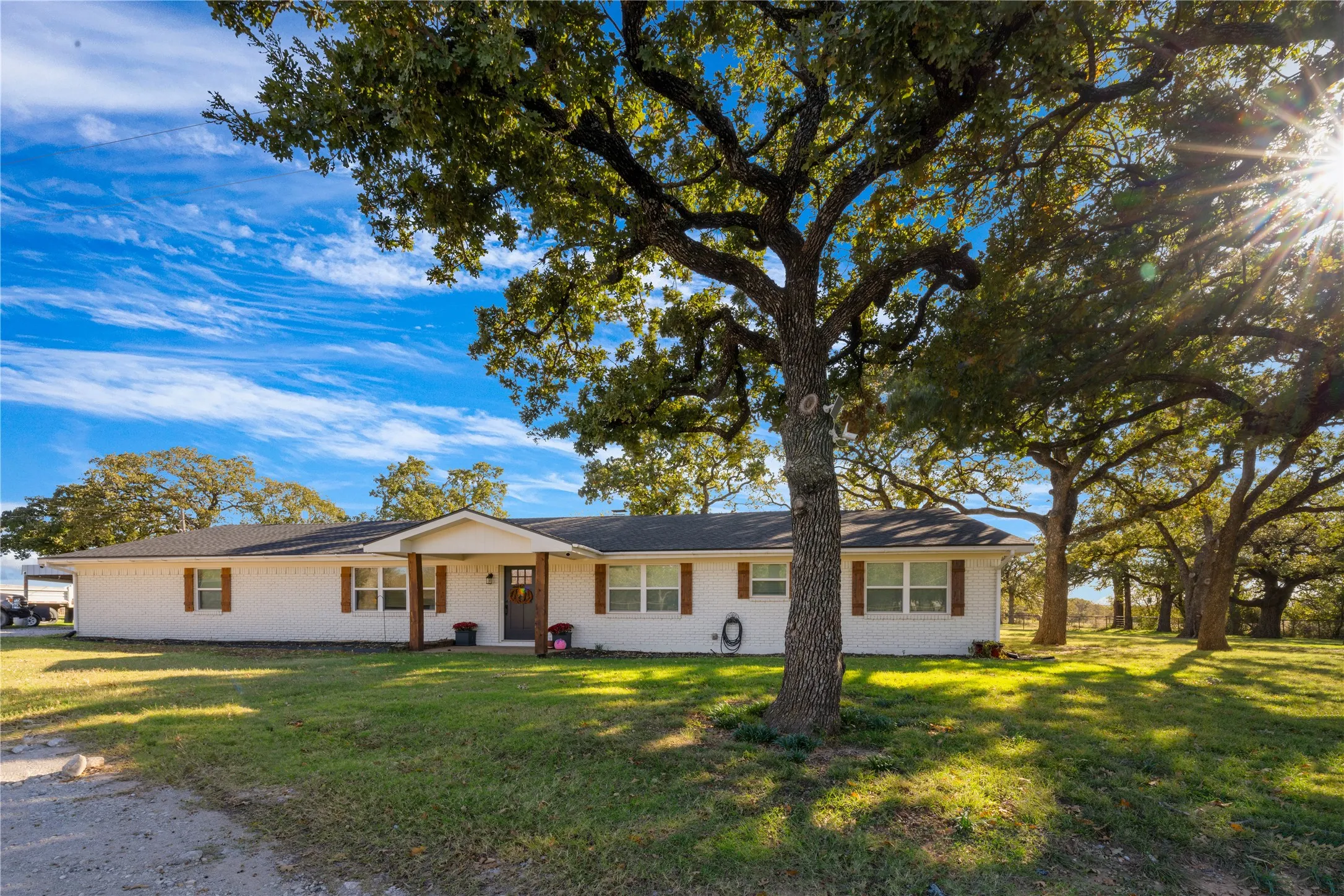 Front view of the home shaded by mature trees.