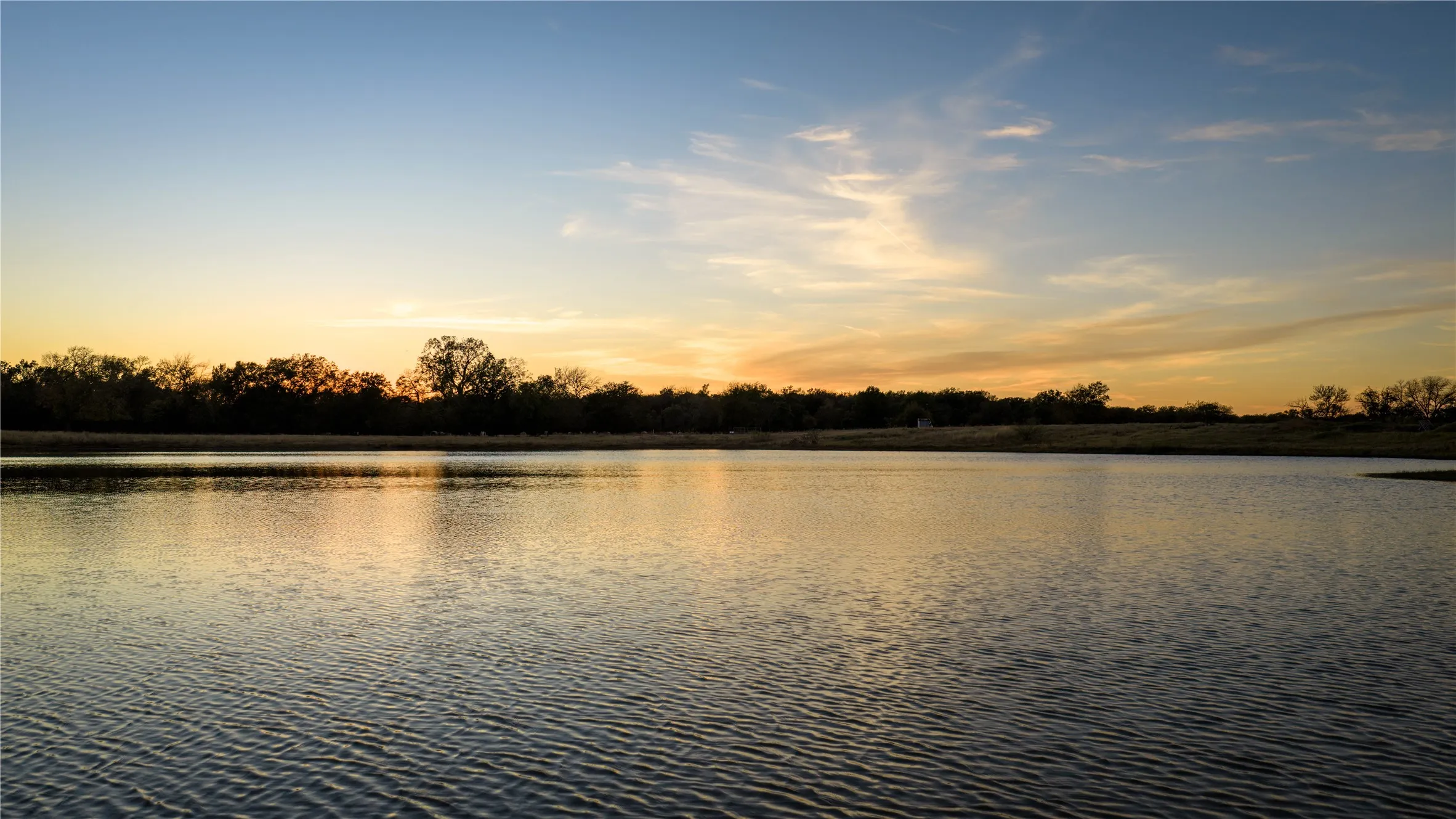 Serene pond view at sunset with reflections on the water.