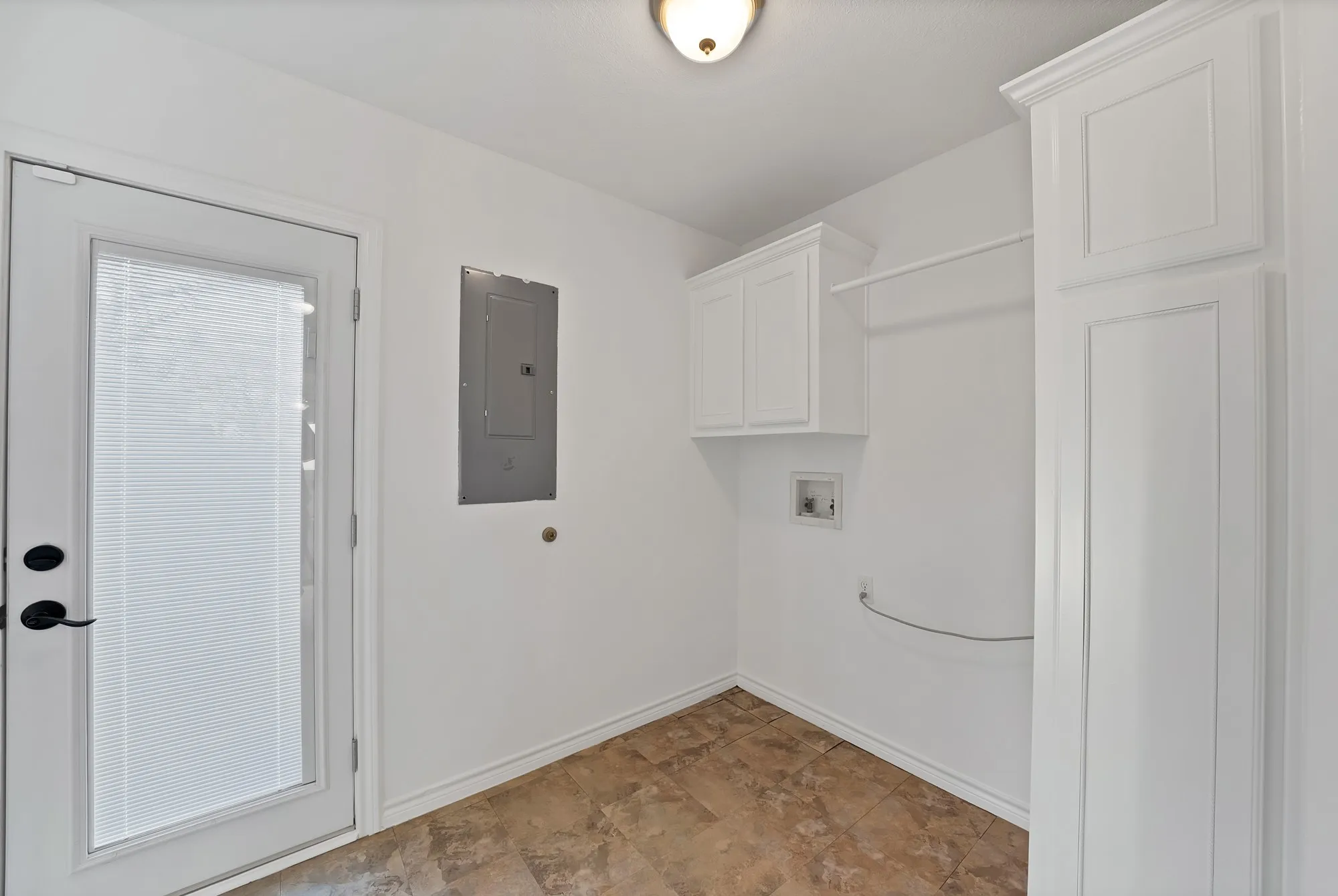 Laundry area with electric panel, hookup for a washing machine, and cabinet space