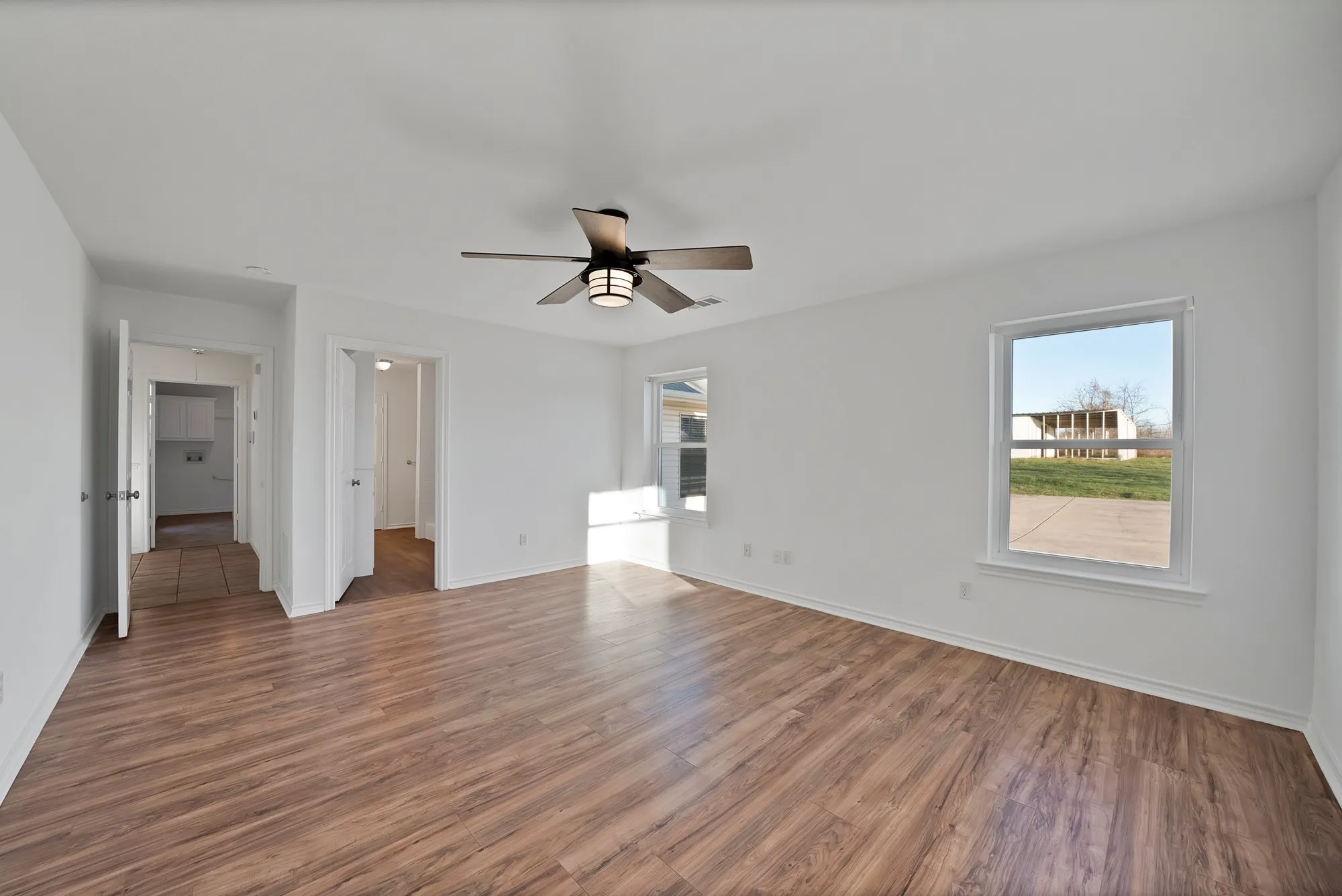 Unfurnished bedroom featuring multiple windows, dark wood-style flooring, and ceiling fan