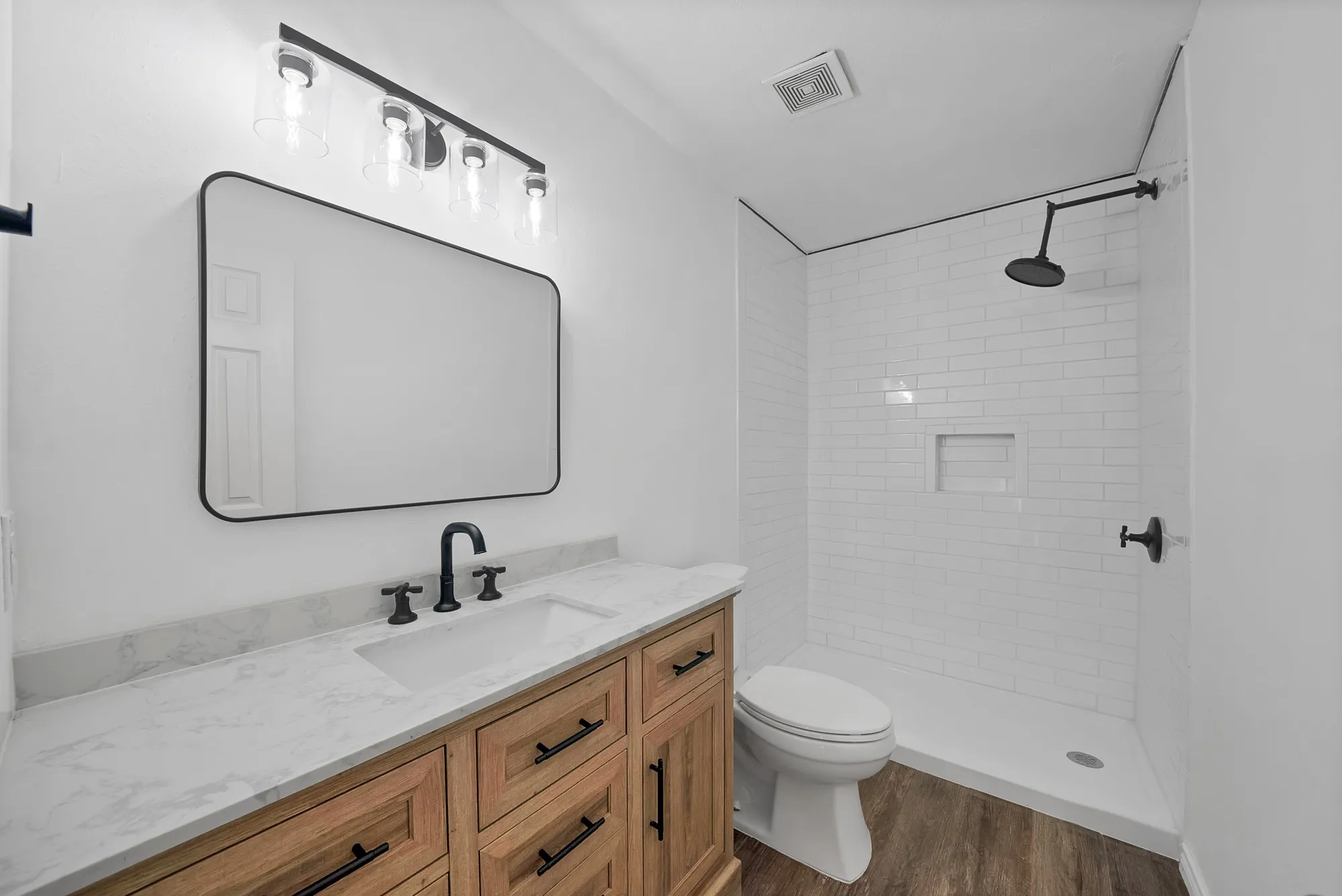 Bathroom featuring vanity, a shower stall, and dark wood-type flooring