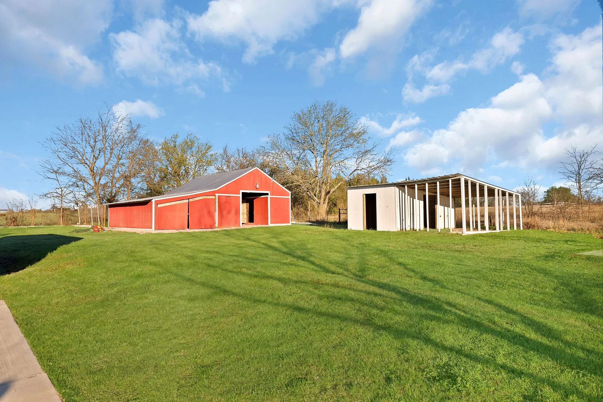 View of grassy yard featuring a pole building and an outbuilding