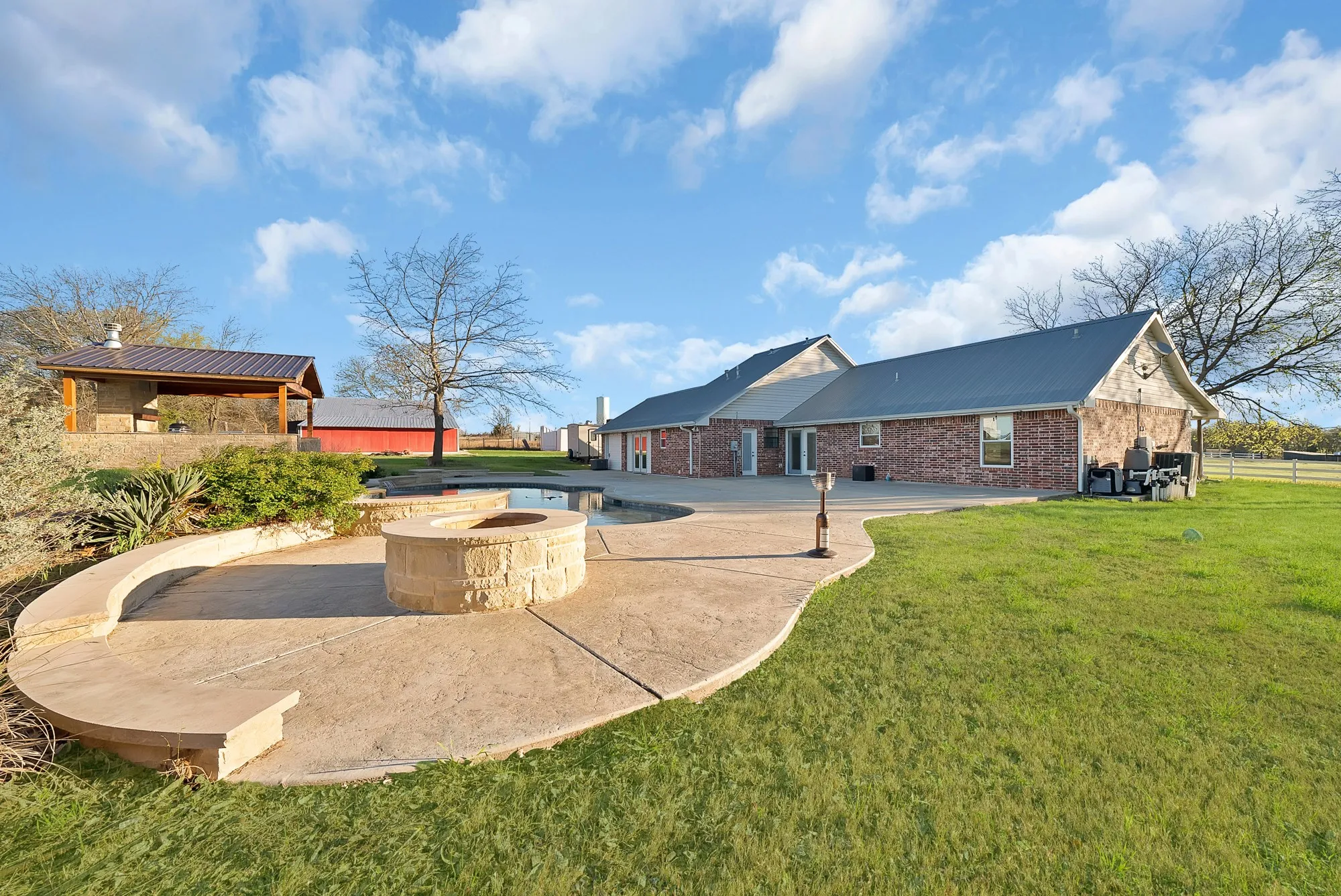 Rear view of property with a patio, a fire pit, brick siding, and a yard
