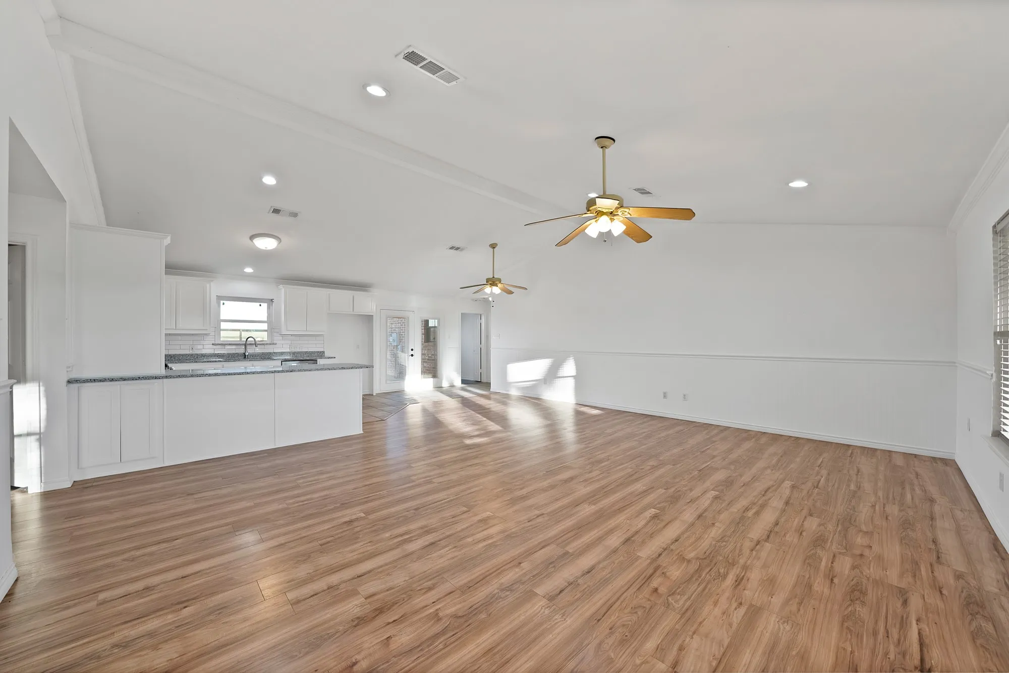 Unfurnished living room featuring light wood-style floors, vaulted ceiling with beams, ceiling fan, and recessed lighting