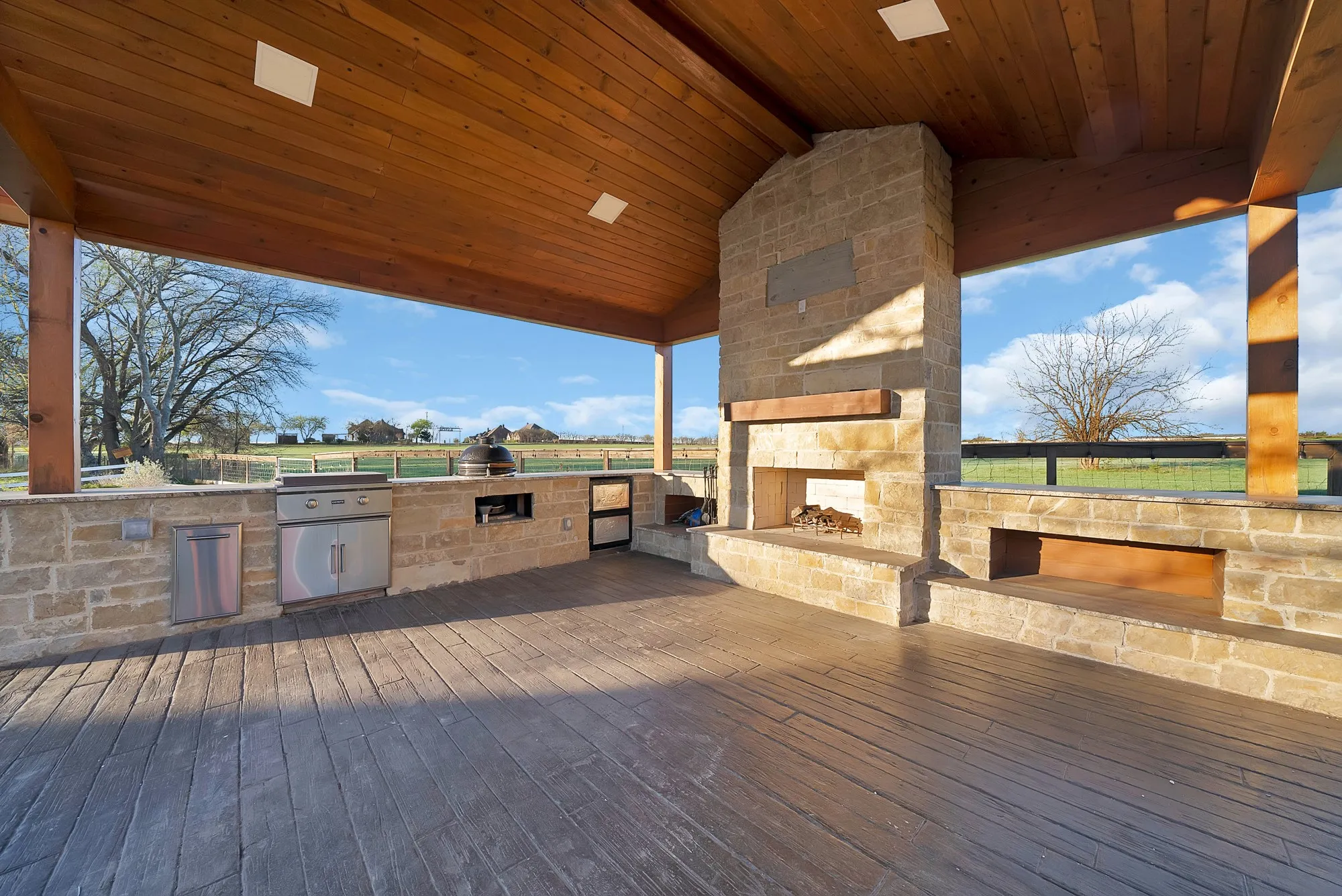 Wooden deck featuring area for grilling and an outdoor stone fireplace
