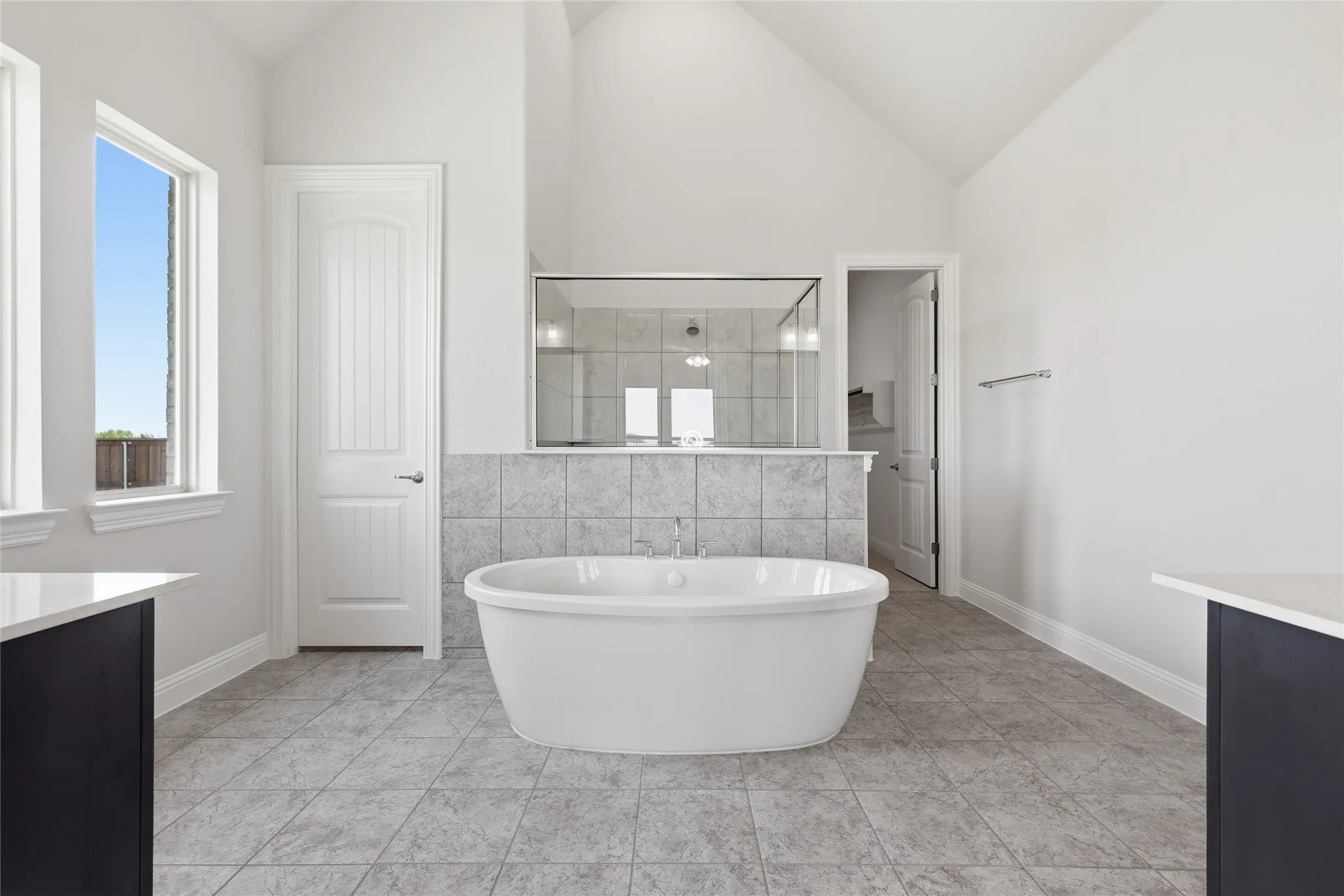 Bathroom with vanity, a shower stall, a soaking tub, vaulted ceiling, and tile walls