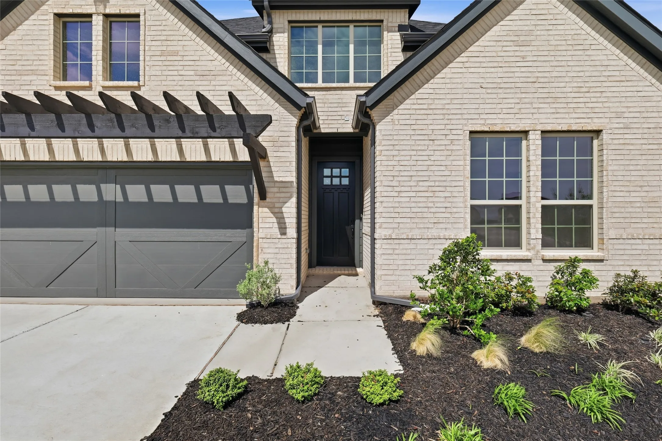View of front facade featuring driveway and brick siding