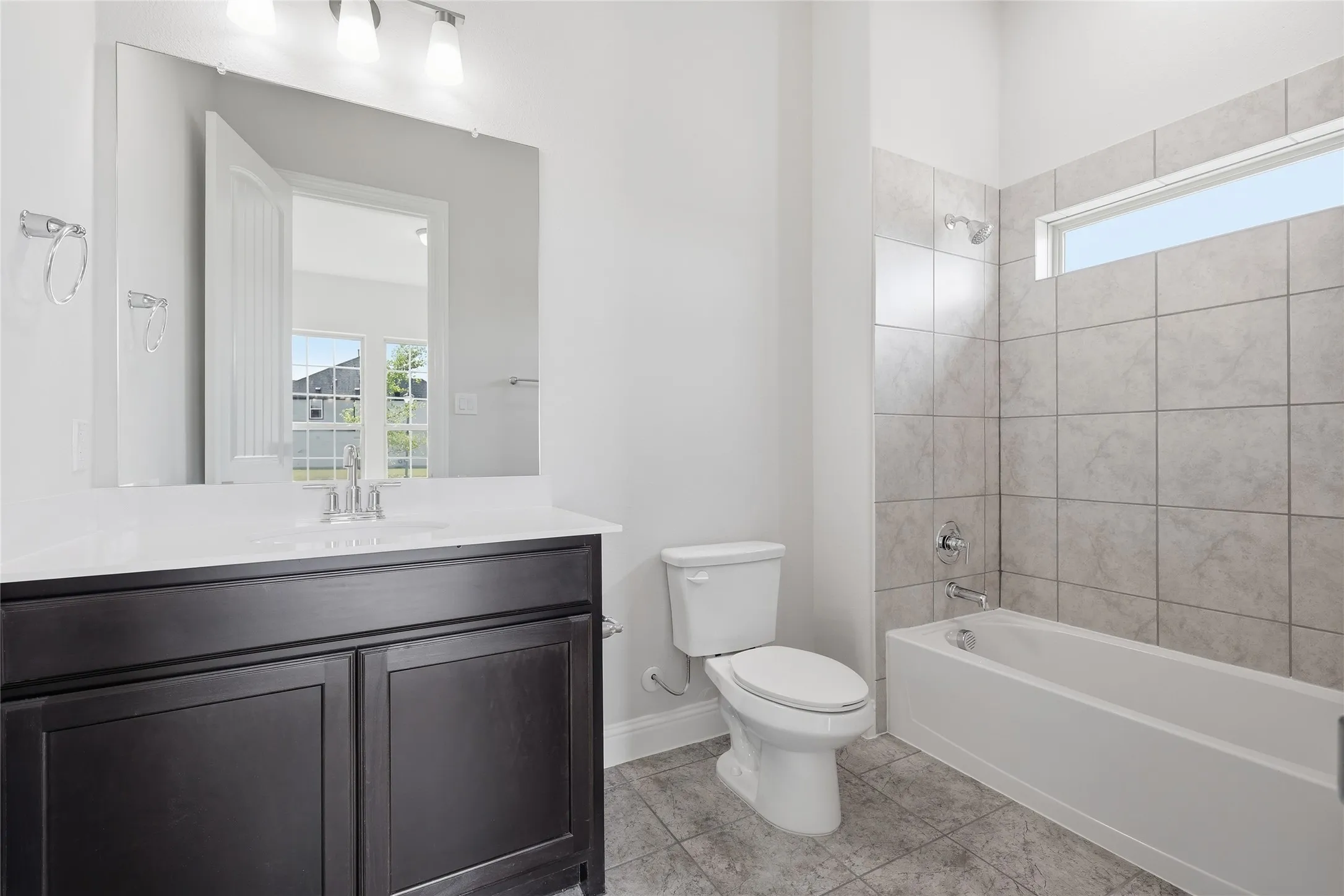 Bathroom featuring healthy amount of natural light, vanity, shower / tub combination, and light tile patterned floors