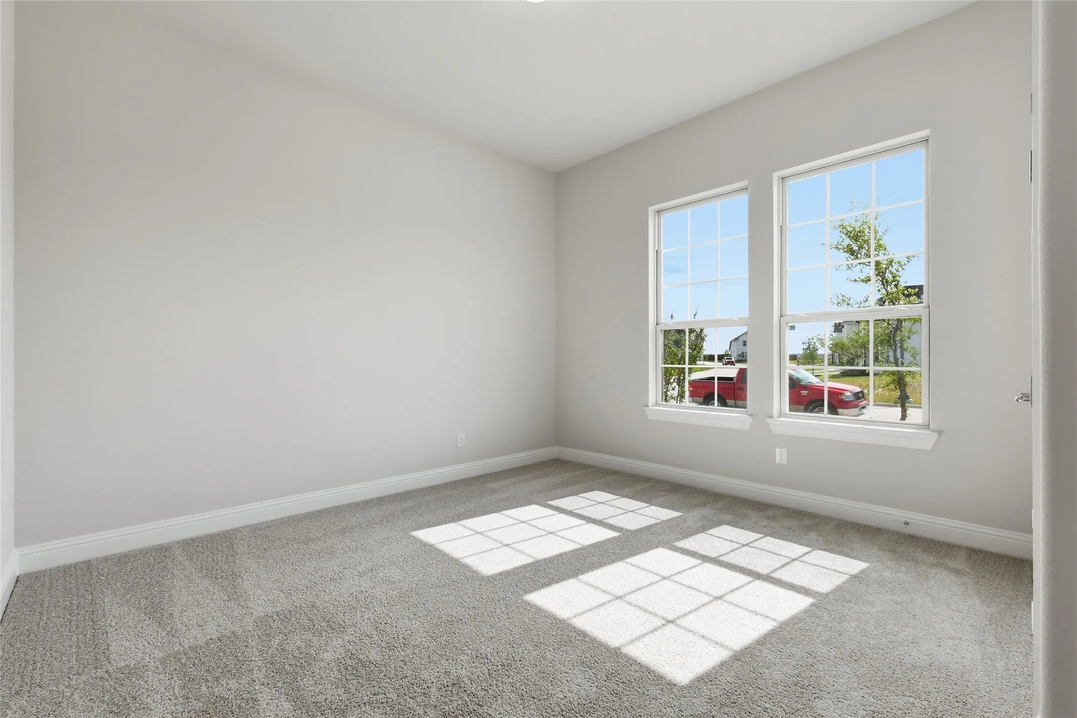 Empty room featuring baseboards and light colored carpet