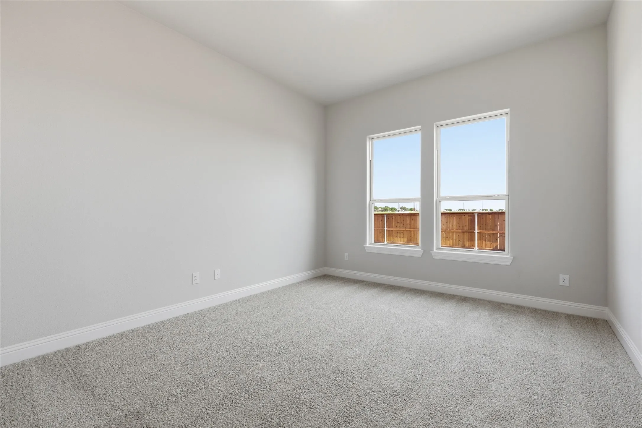 Empty room featuring light colored carpet and baseboards