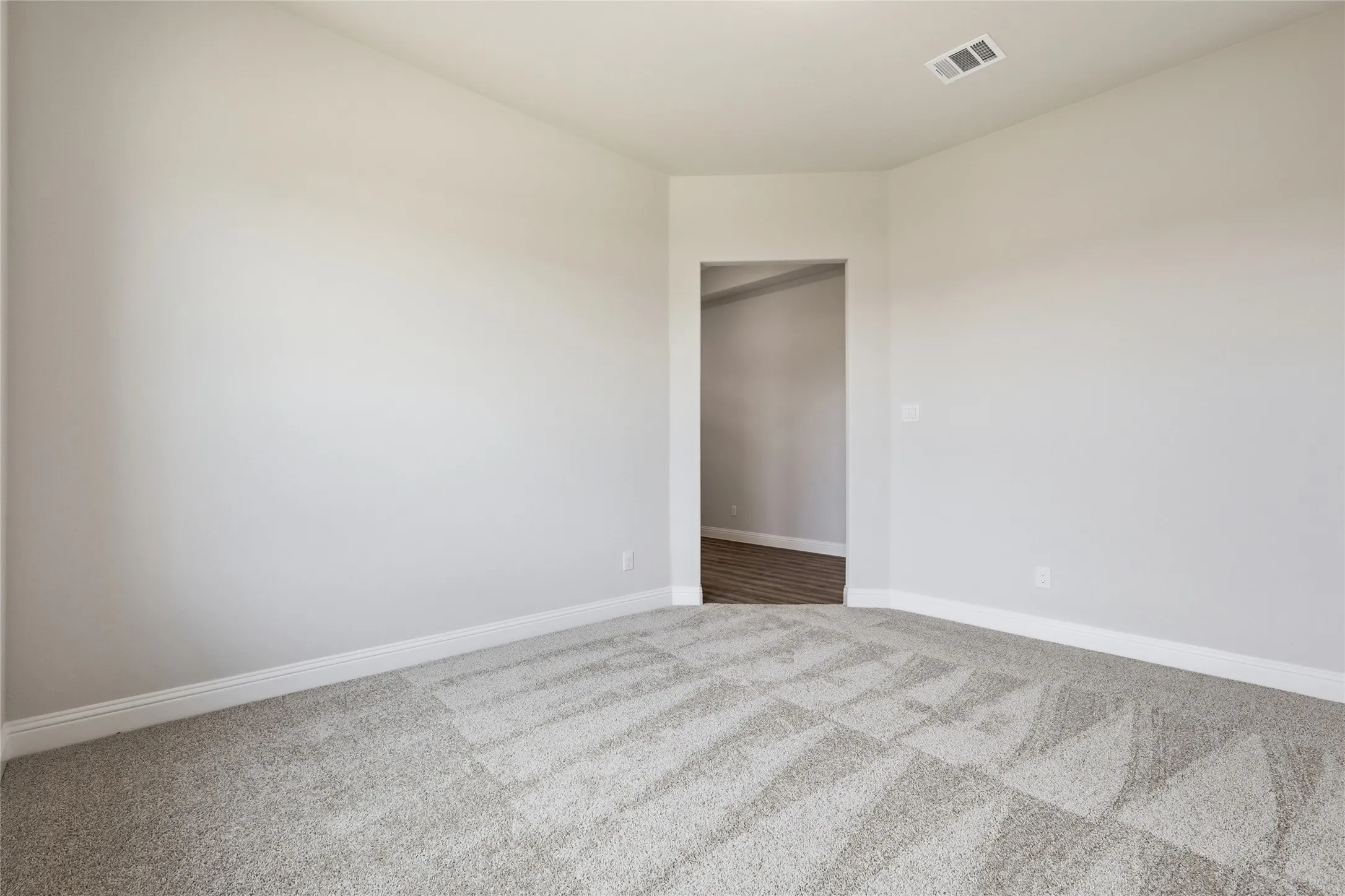 Empty room featuring light colored carpet and baseboards