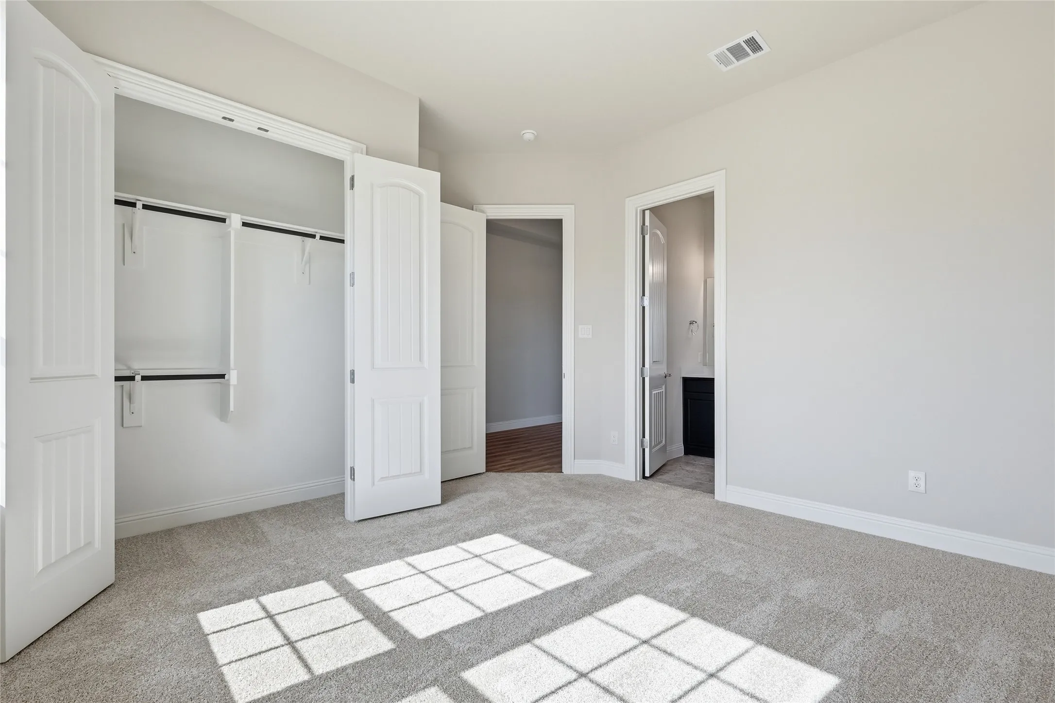 Unfurnished bedroom featuring light colored carpet, a closet, and ensuite bath