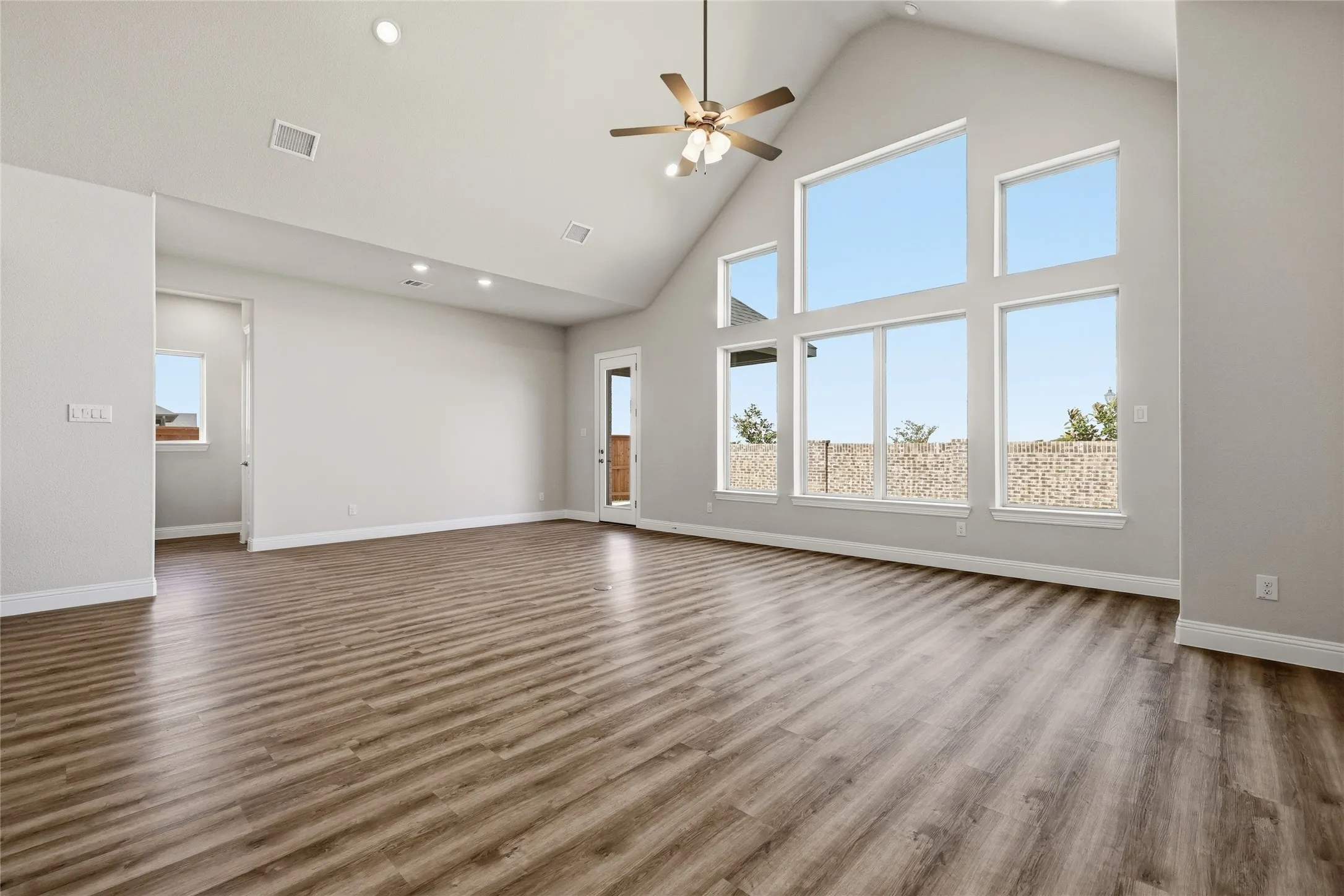 Unfurnished living room with a ceiling fan, a high ceiling, dark wood-style floors, and recessed lighting