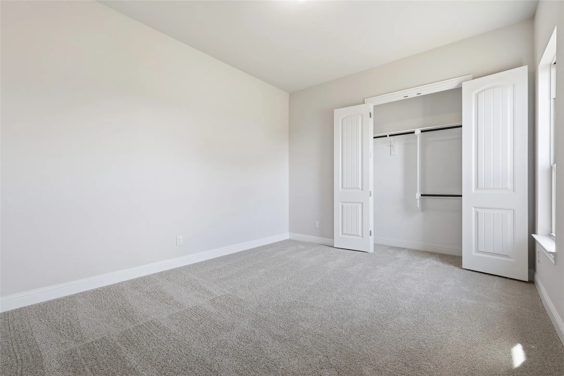 Unfurnished bedroom with light colored carpet and a closet