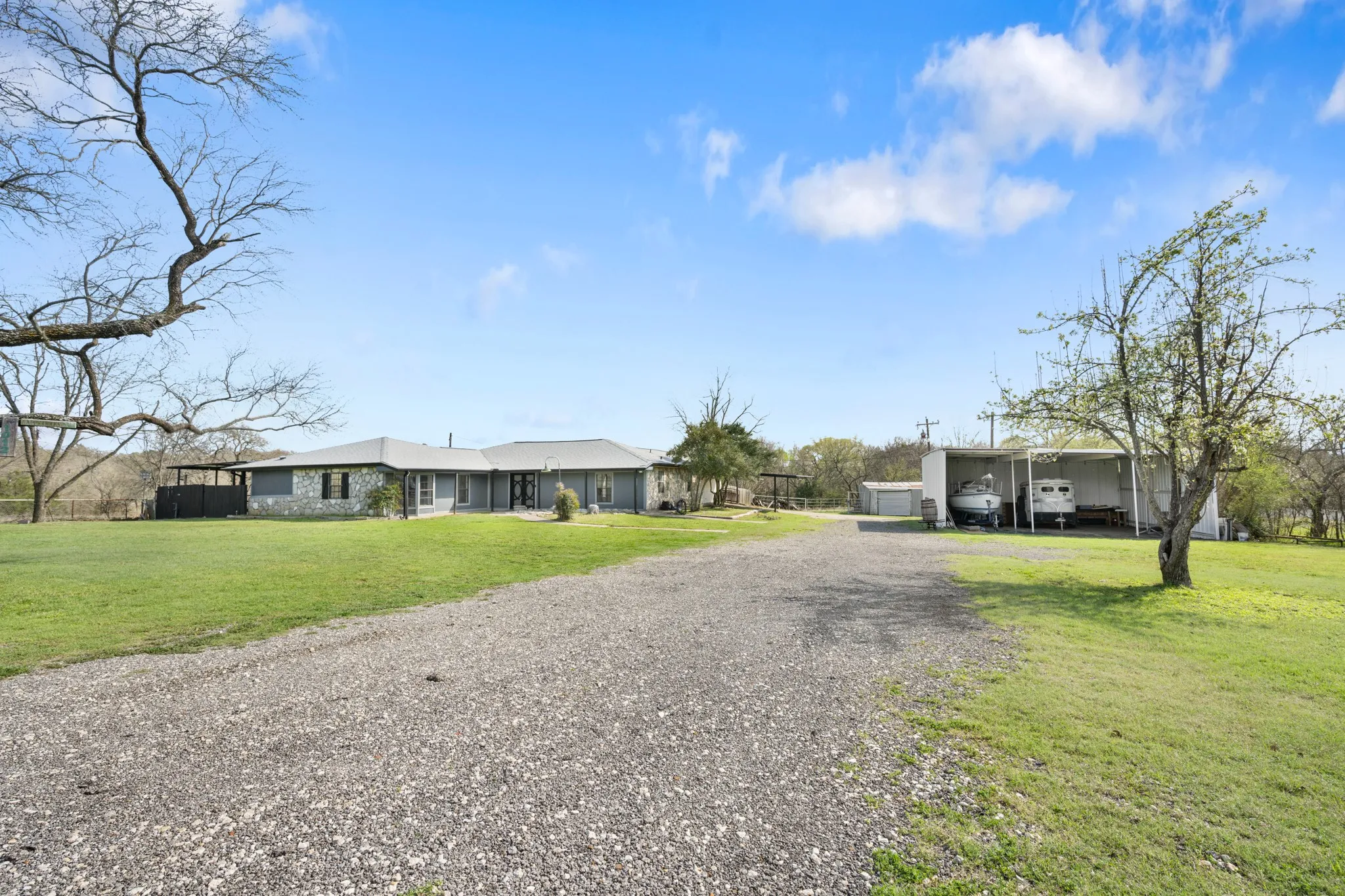 View of front of house with a front lawn, gravel driveway, and a carport