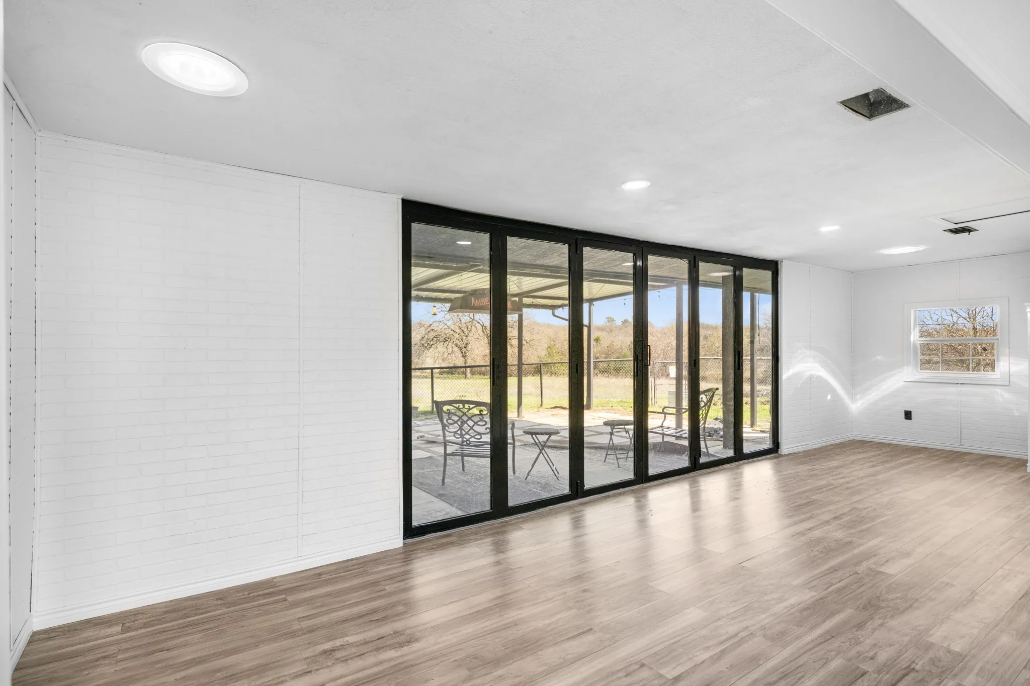 Spare room with wood finished floors, brick wall, floor to ceiling windows, and recessed lighting