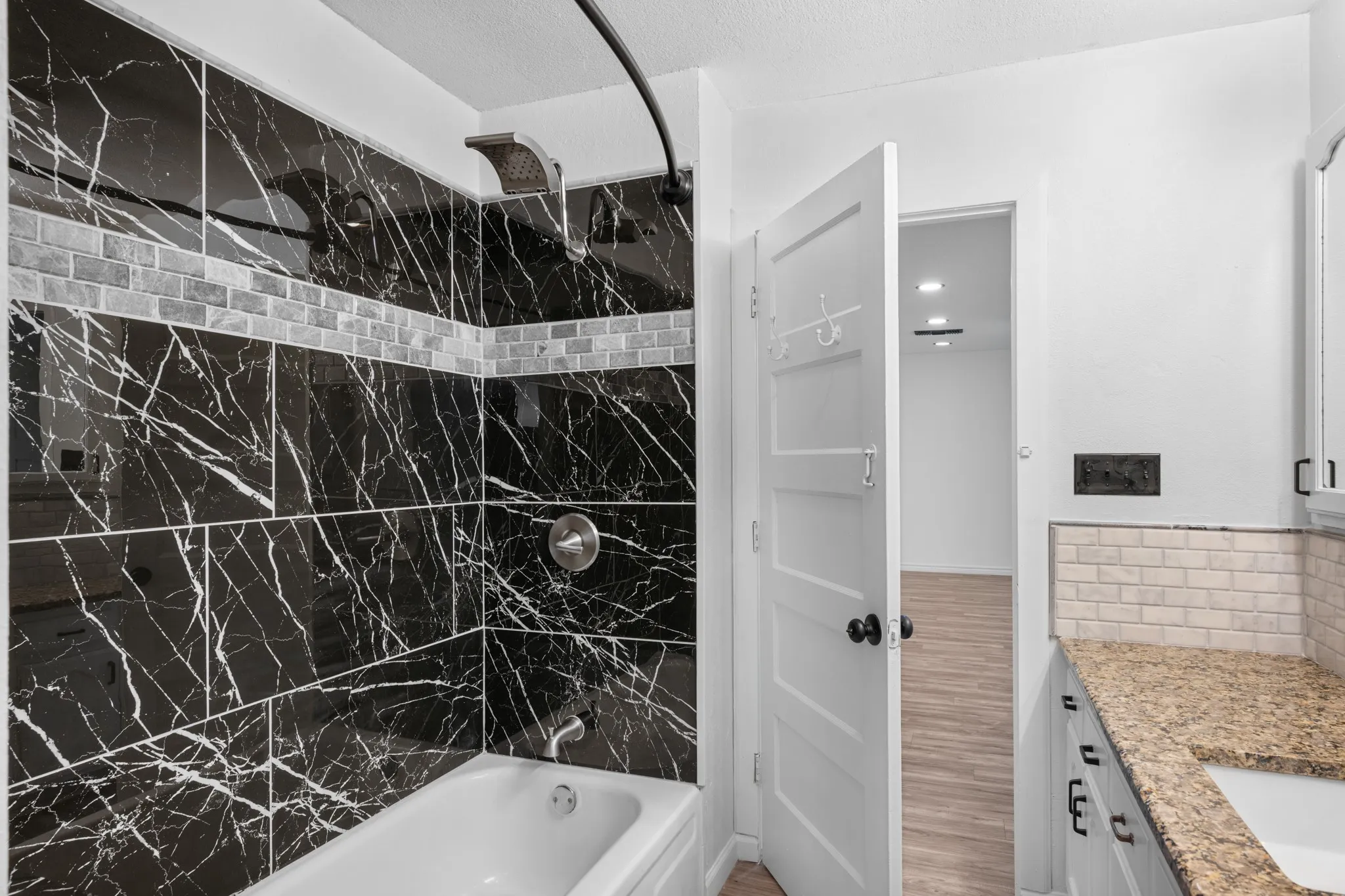 Bathroom featuring vanity, shower / tub combination, a textured ceiling, and backsplash