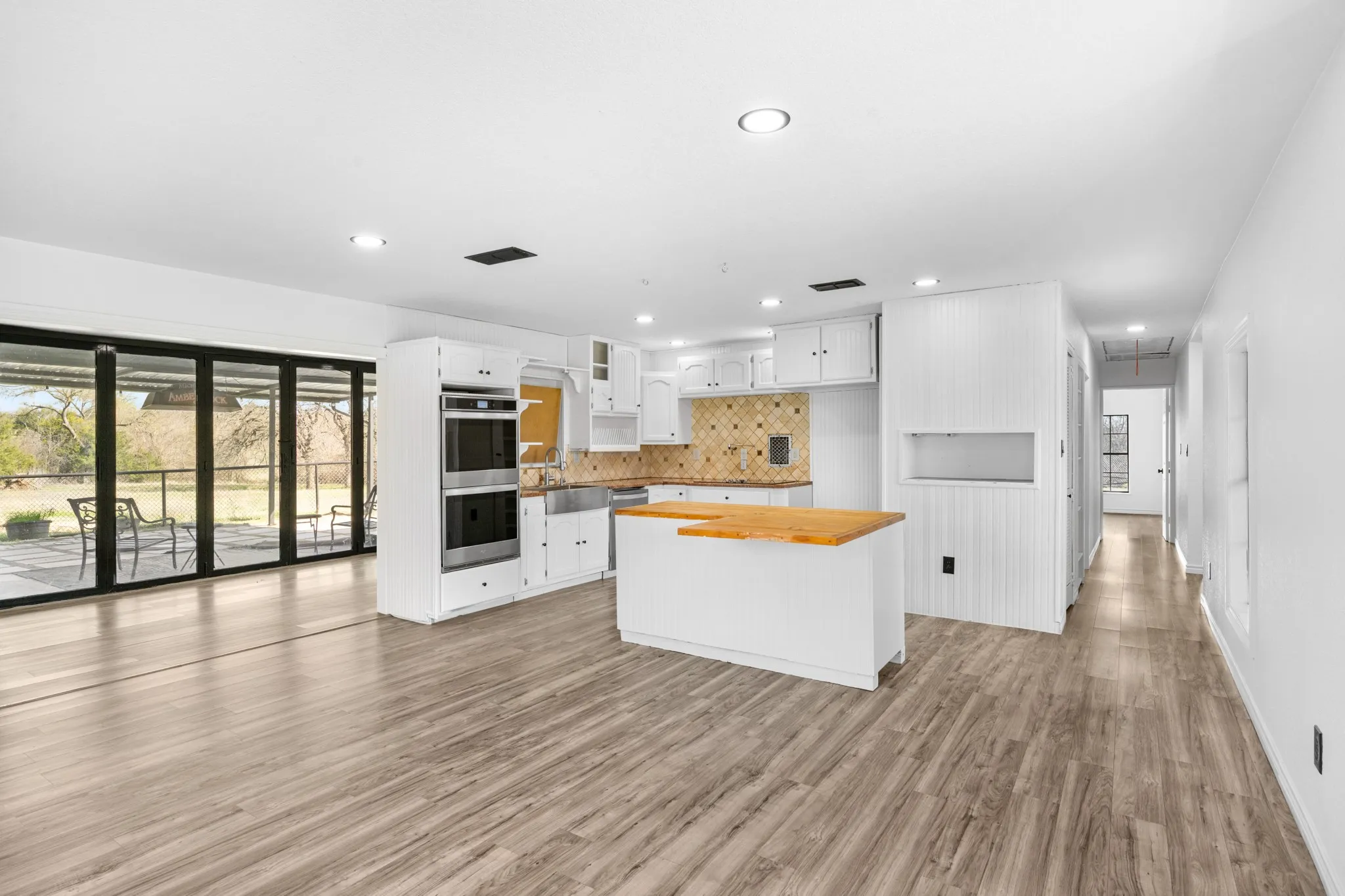 Kitchen with a center island, backsplash, white cabinets, stainless steel appliances, and light wood-style flooring